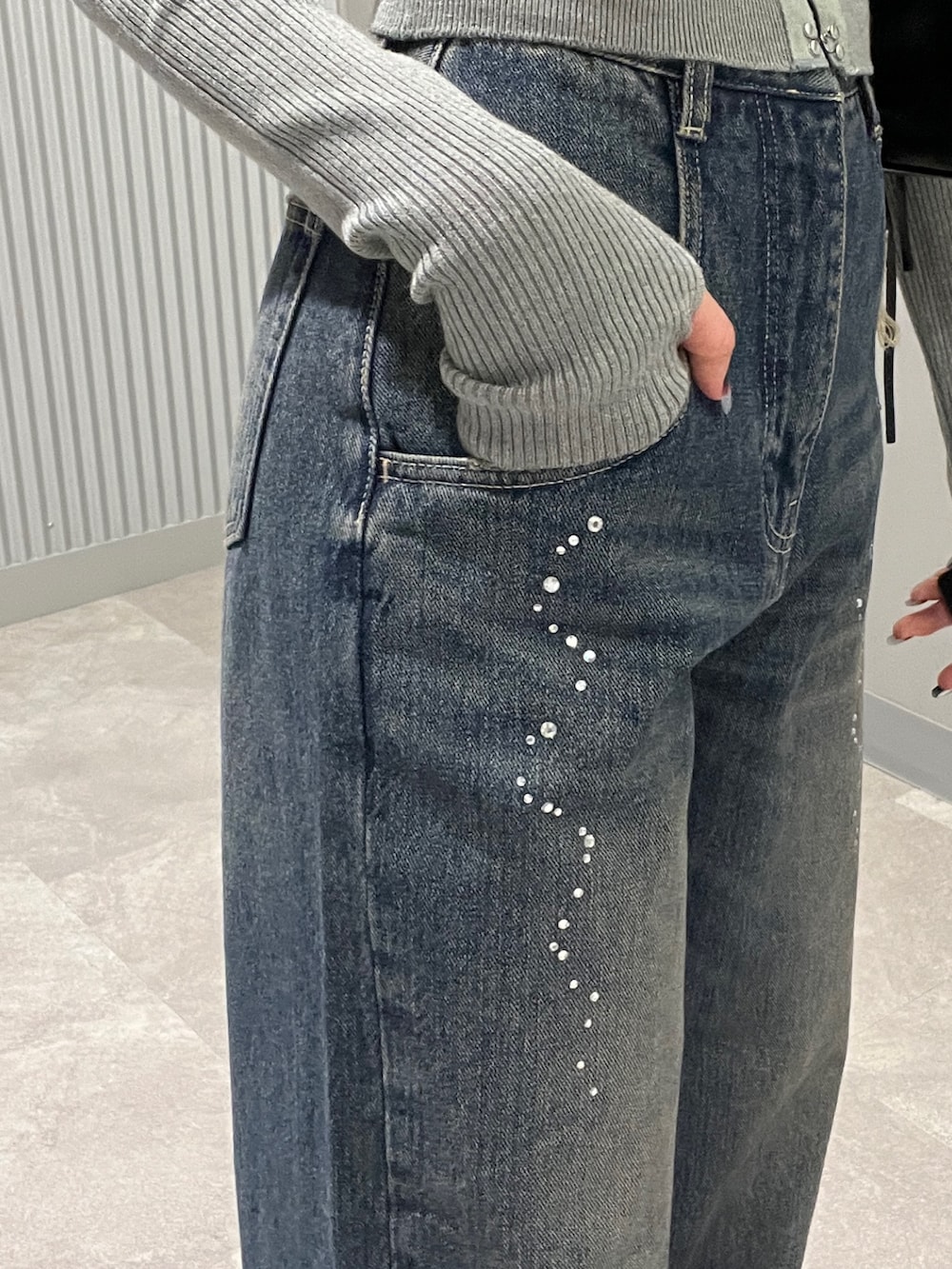 グレー系のニット/セーター、ブルー系のデニムパンツ、ブラック系のショルダーバッグを着用したレディースの秋コーディネートの6枚目の写真