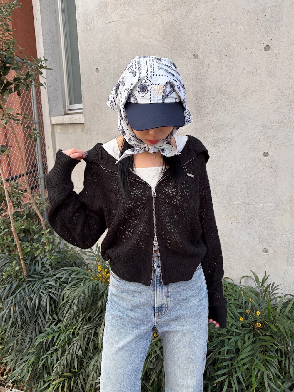 ブラック系のパーカー、ホワイト系のニット/セーター、ブルー系のデニムパンツを着用したレディースの春コーディネートの4枚目の写真