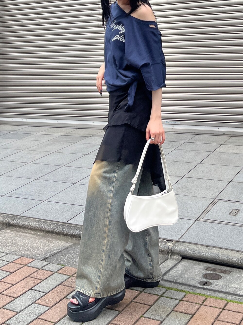 ブルー系のTシャツ/カットソー、ブラック系のスカート、ブルー系のデニムパンツを着用したレディースの春コーディネートの2枚目の写真