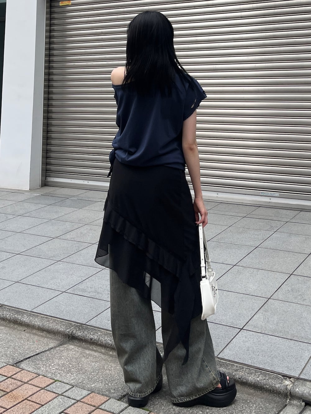 ブルー系のTシャツ/カットソー、ブラック系のスカート、ブルー系のデニムパンツを着用したレディースの春コーディネートの3枚目の写真