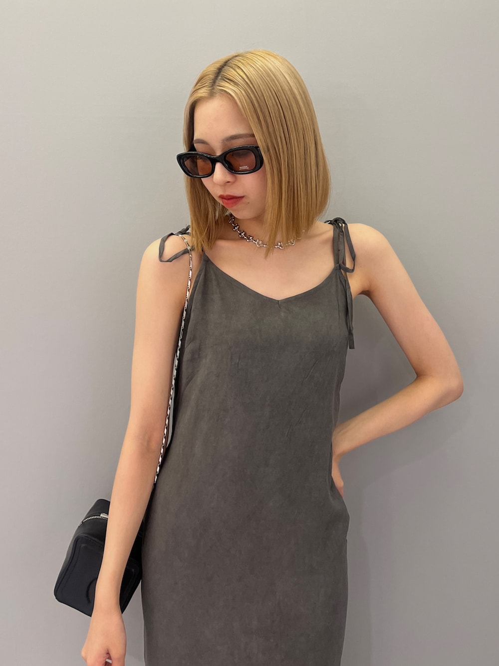 ブラック系のハンドバッグ、ブラック系のワンピース、ブラック系のサンダルを着用したレディースの夏コーディネートの4枚目の写真