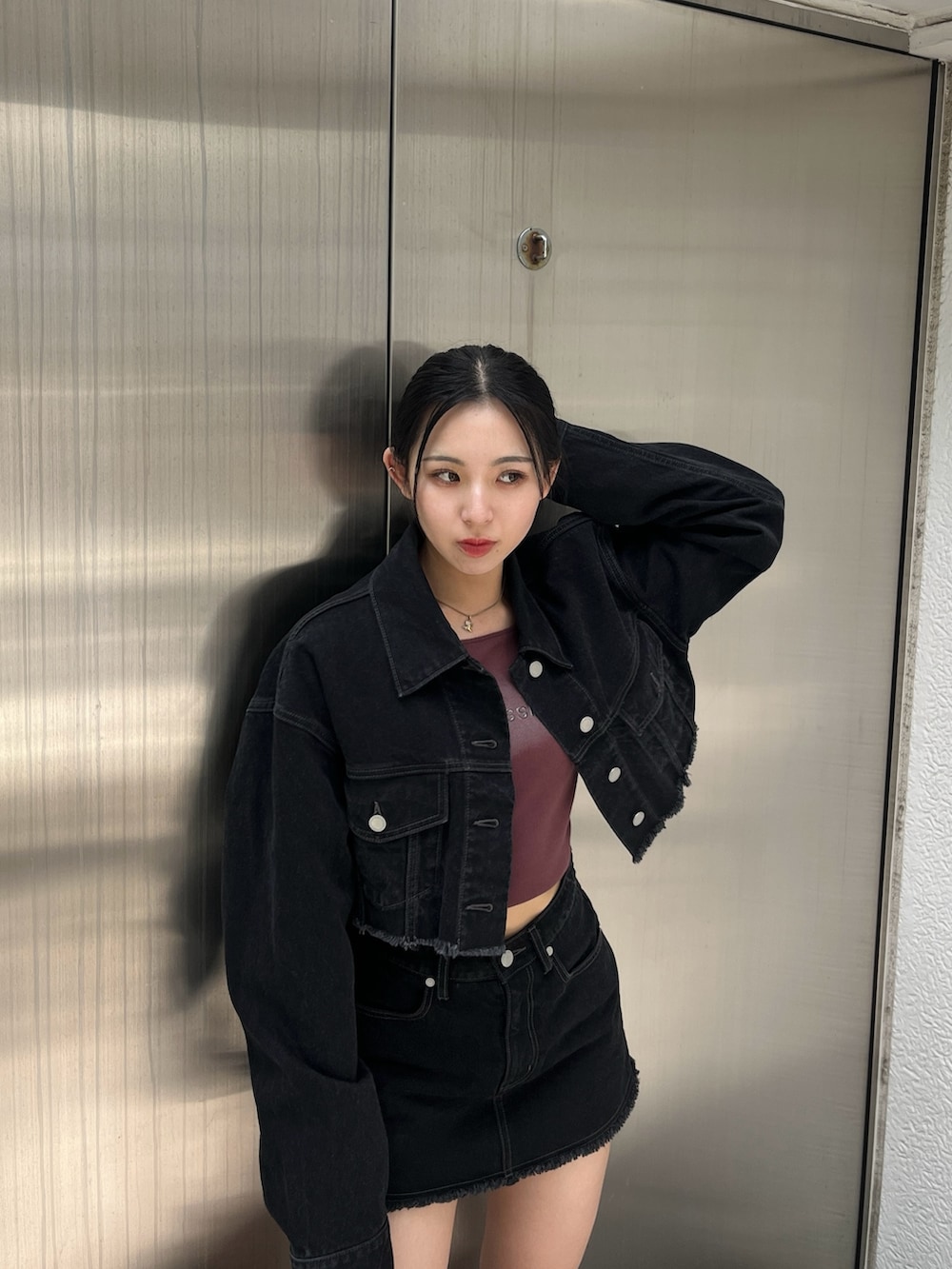 ブラック系のデニムジャケット、ブラック系のスカート、レッド系のTシャツ/カットソーを着用したレディースの夏コーディネートの4枚目の写真