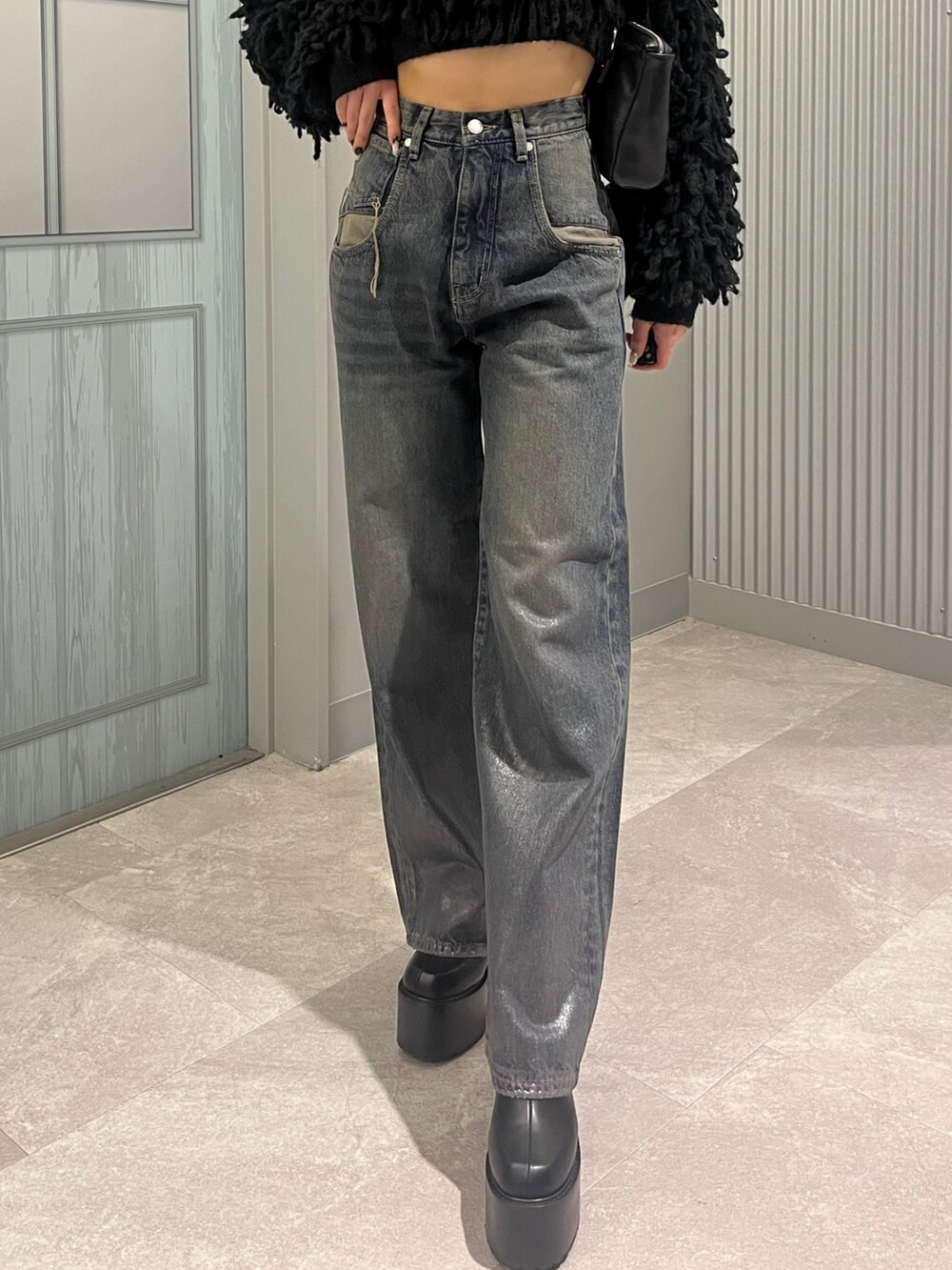 ブルー系のデニムパンツ、ブラック系のニット/セーター、ブラック系のショルダーバッグを着用したレディースの秋コーディネートの5枚目の写真