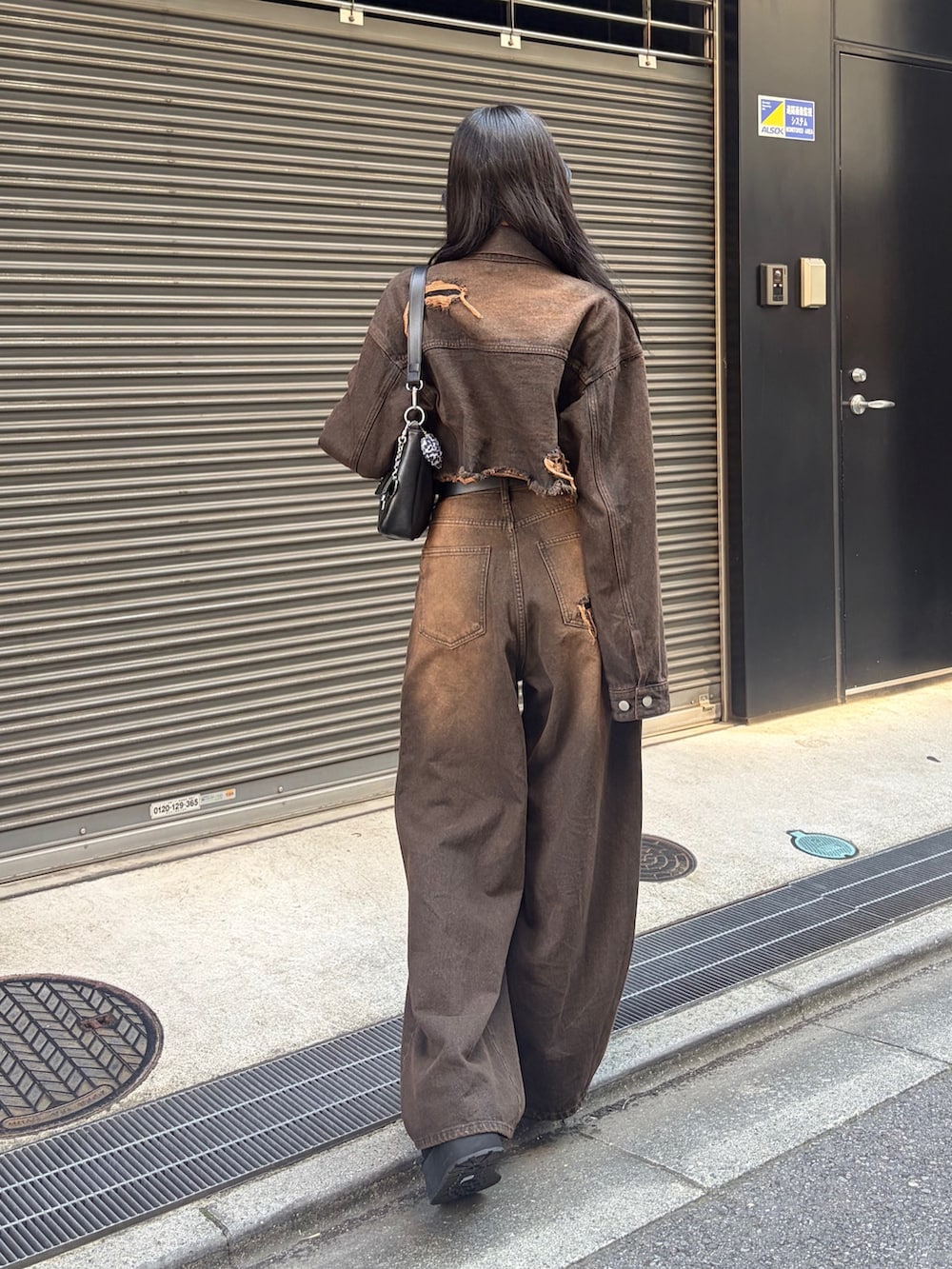 ブラック系のTシャツ/カットソー、ブラウン系のデニムパンツ、ブラック系のハンドバッグを着用したレディースの秋コーディネートの3枚目の写真
