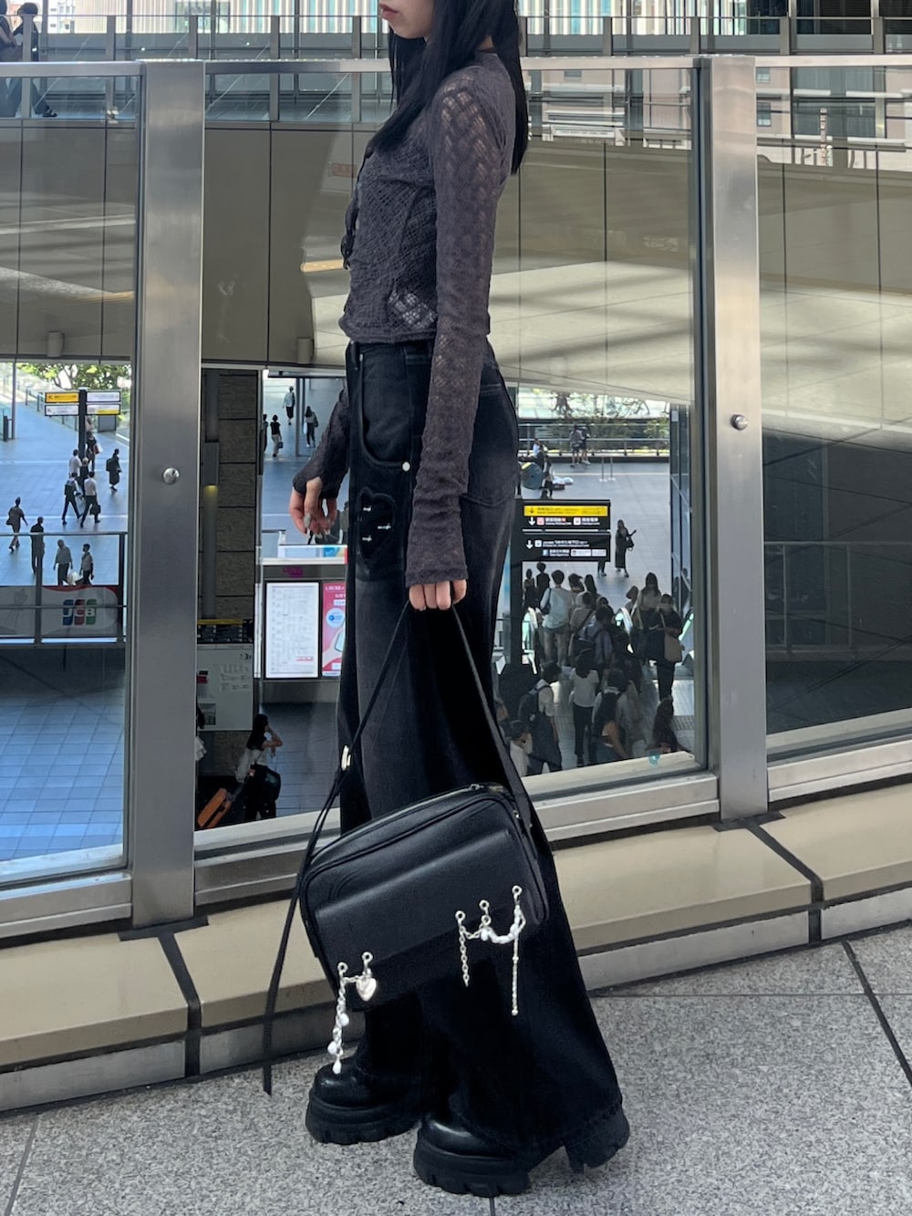 グレー系のTシャツ/カットソー、ブラック系のハンドバッグ、ブラック系のデニムパンツを着用したレディースの秋コーディネートの2枚目の写真