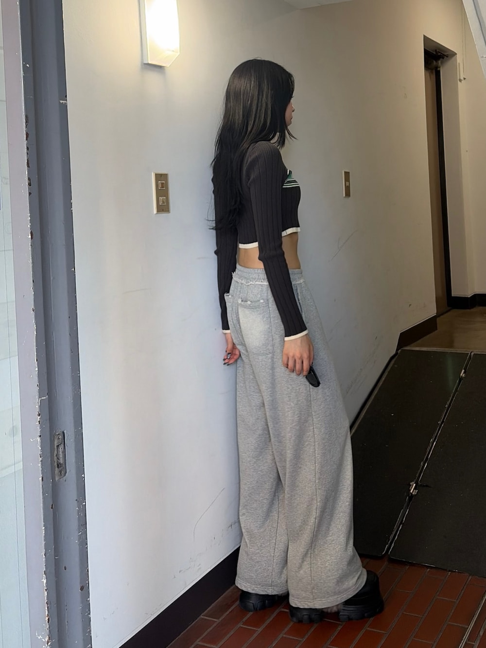 グレー系のニット/セーター、ブラック系のブーツ、ブラック系のメガネを着用したレディースの秋コーディネートの2枚目の写真
