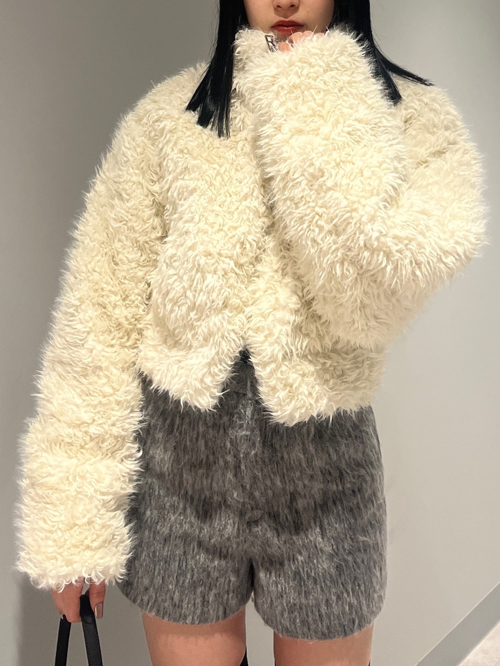 ホワイト系のブルゾン、ブラック系のカーディガン/ボレロ、グレー系のその他パンツを着用したレディースの冬コーディネートの5枚目の写真