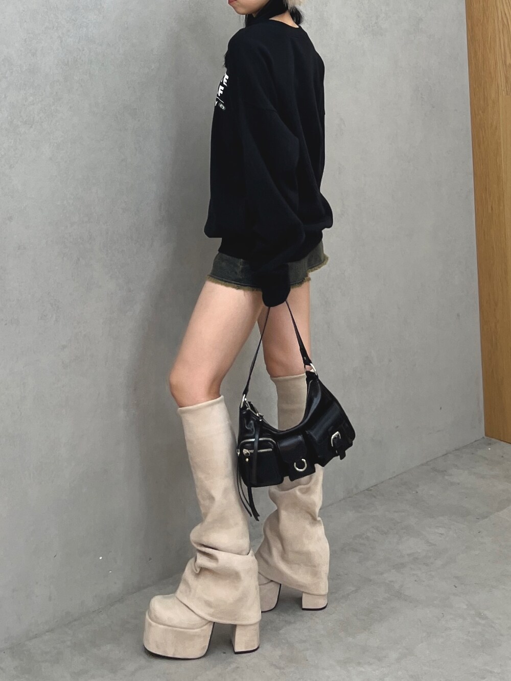 ブラック系のスウェット、ブルー系のスカート、ブラック系のハンドバッグを着用したレディースの秋コーディネートの2枚目の写真