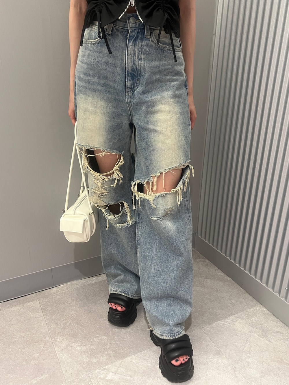 ブルー系のデニムパンツ、ホワイト系のハンドバッグ、ブラック系のTシャツ/カットソーを着用したレディースの夏コーディネートの5枚目の写真