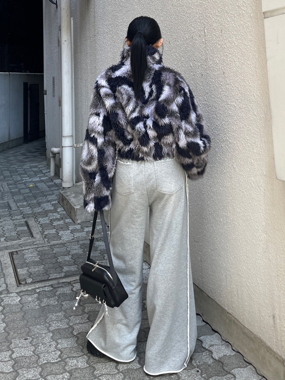 ブルー系のブルゾン、グレー系のスウェットパンツ、ブラック系のハンドバッグを着用したレディースの秋コーディネートの3枚目の写真