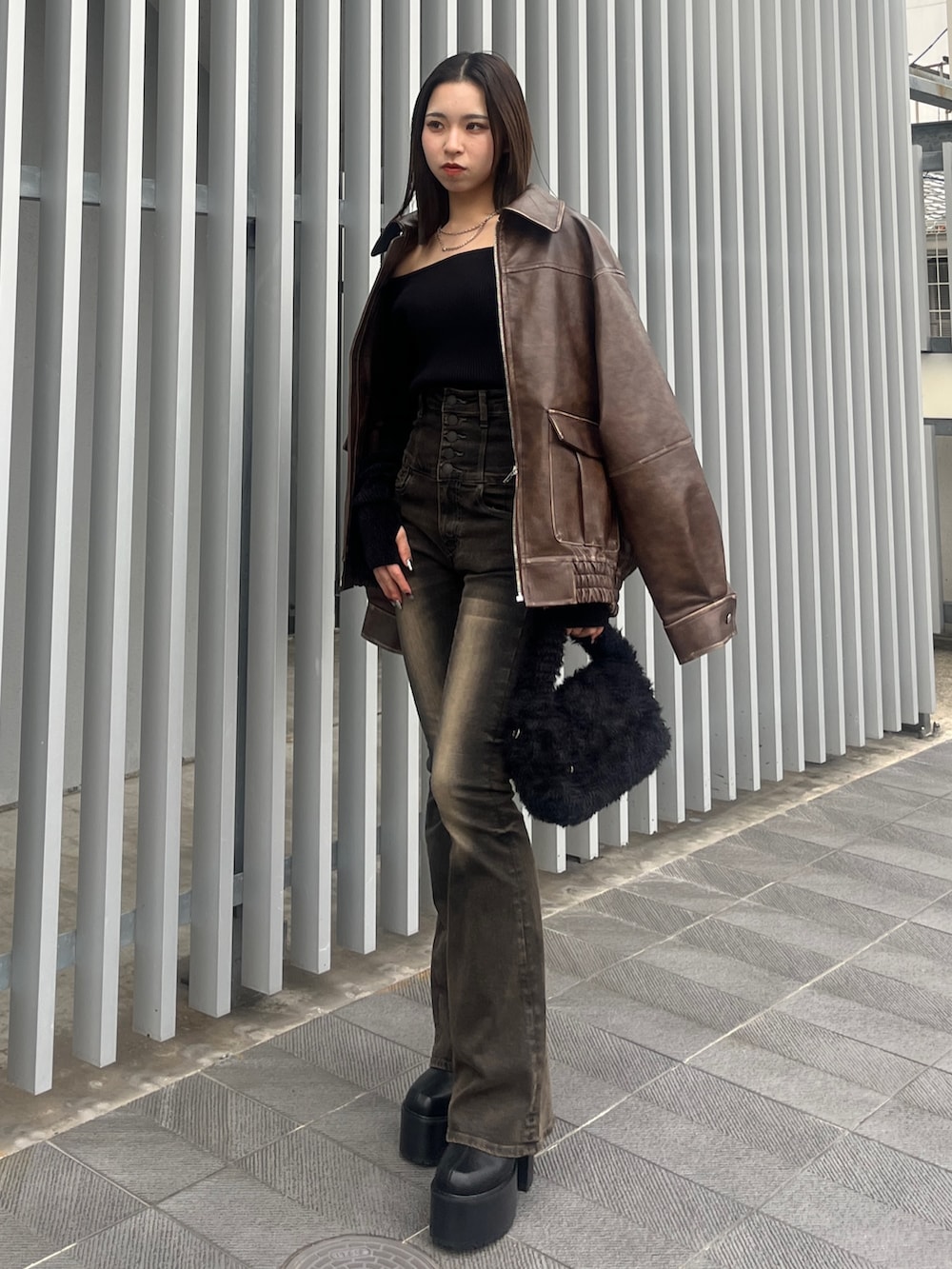 ブラック系のデニムパンツ、ブラウン系のブルゾン、ブラック系のハンドバッグを着用したレディースの秋コーディネートの4枚目の写真