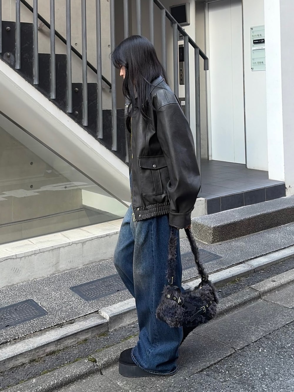 ブラック系のブルゾン、ブラック系のTシャツ/カットソー、ブルー系のデニムパンツを着用したレディースの秋コーディネートの2枚目の写真
