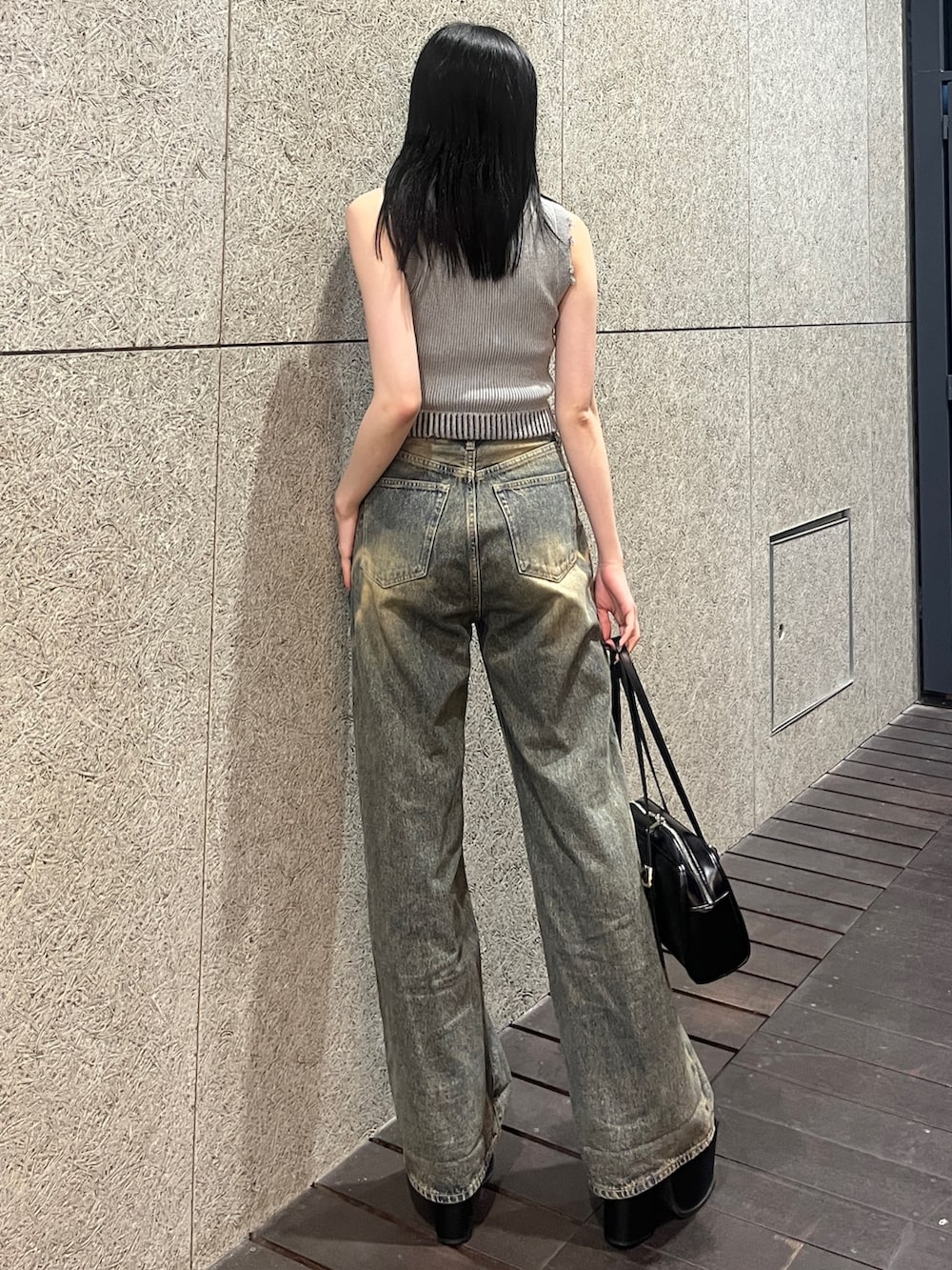 グレー系のタンクトップ、ブルー系のデニムパンツ、ブラック系のハンドバッグを着用したレディースの春コーディネートの3枚目の写真
