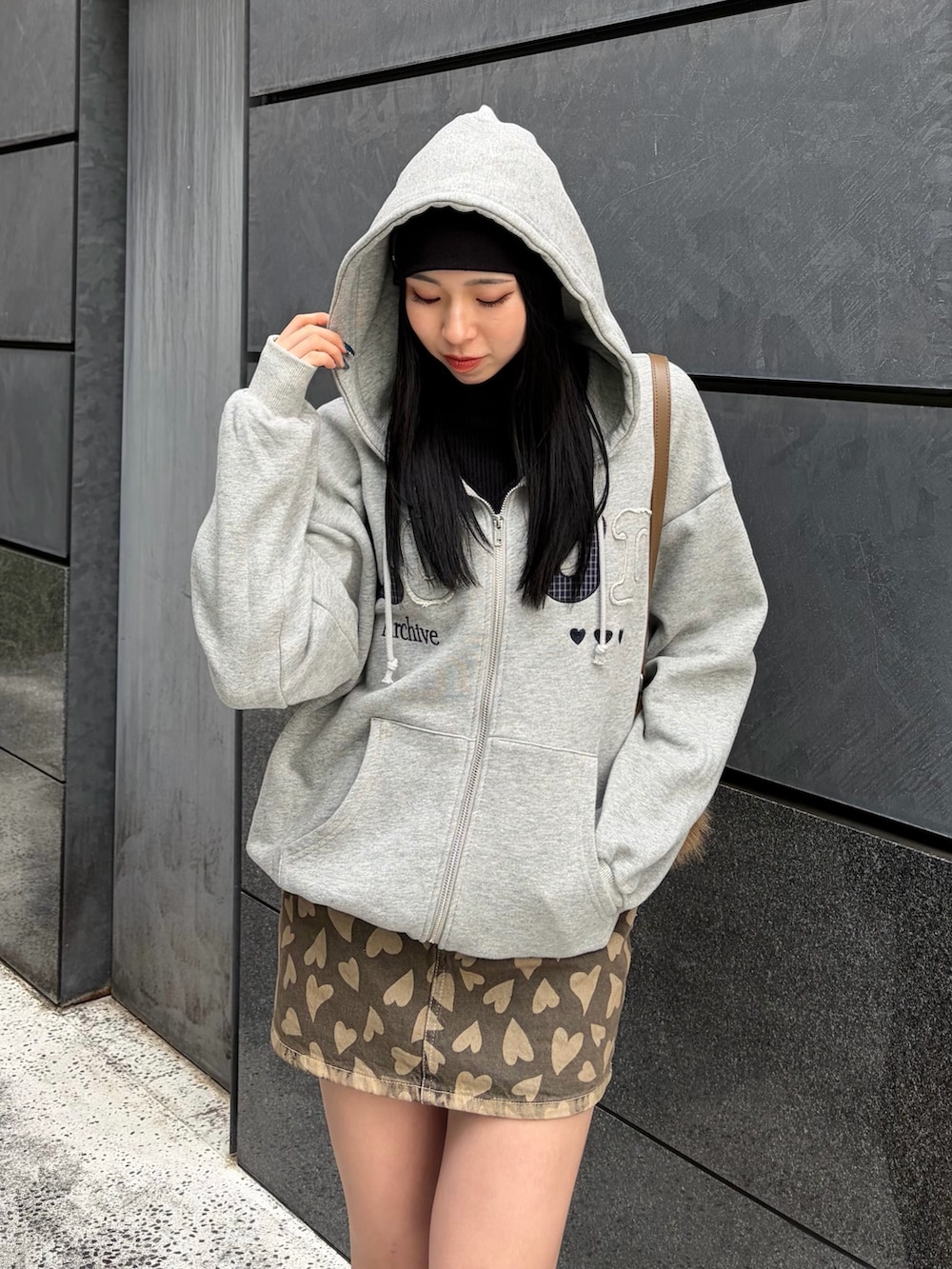 グレー系のパーカー、ベージュ系のスカート、ベージュ系のショルダーバッグを着用したレディースの冬コーディネートの3枚目の写真