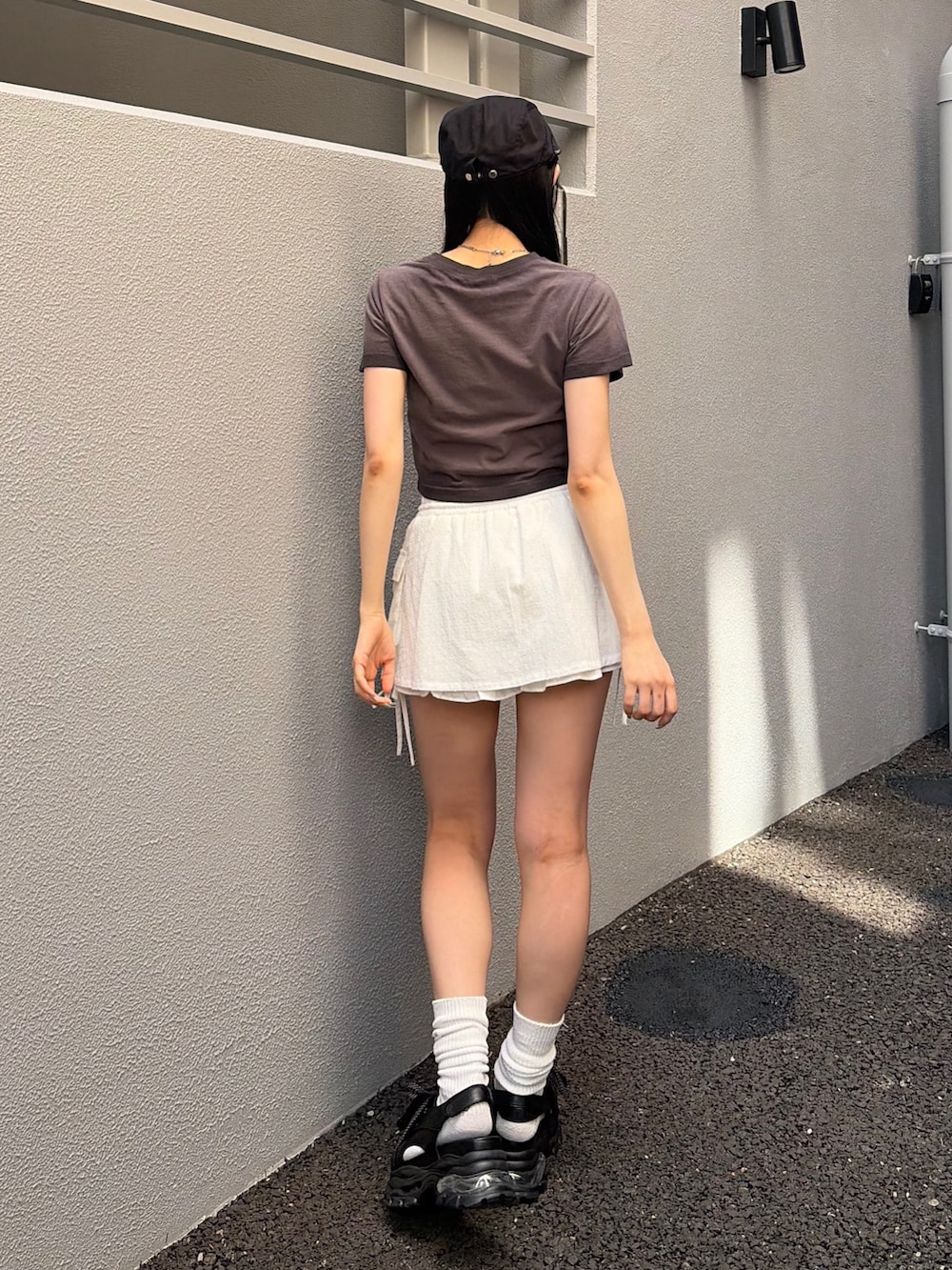 ブラック系のTシャツ/カットソー、ホワイト系のスカート、ブラック系のサンダルを着用したレディースの夏コーディネートの2枚目の写真