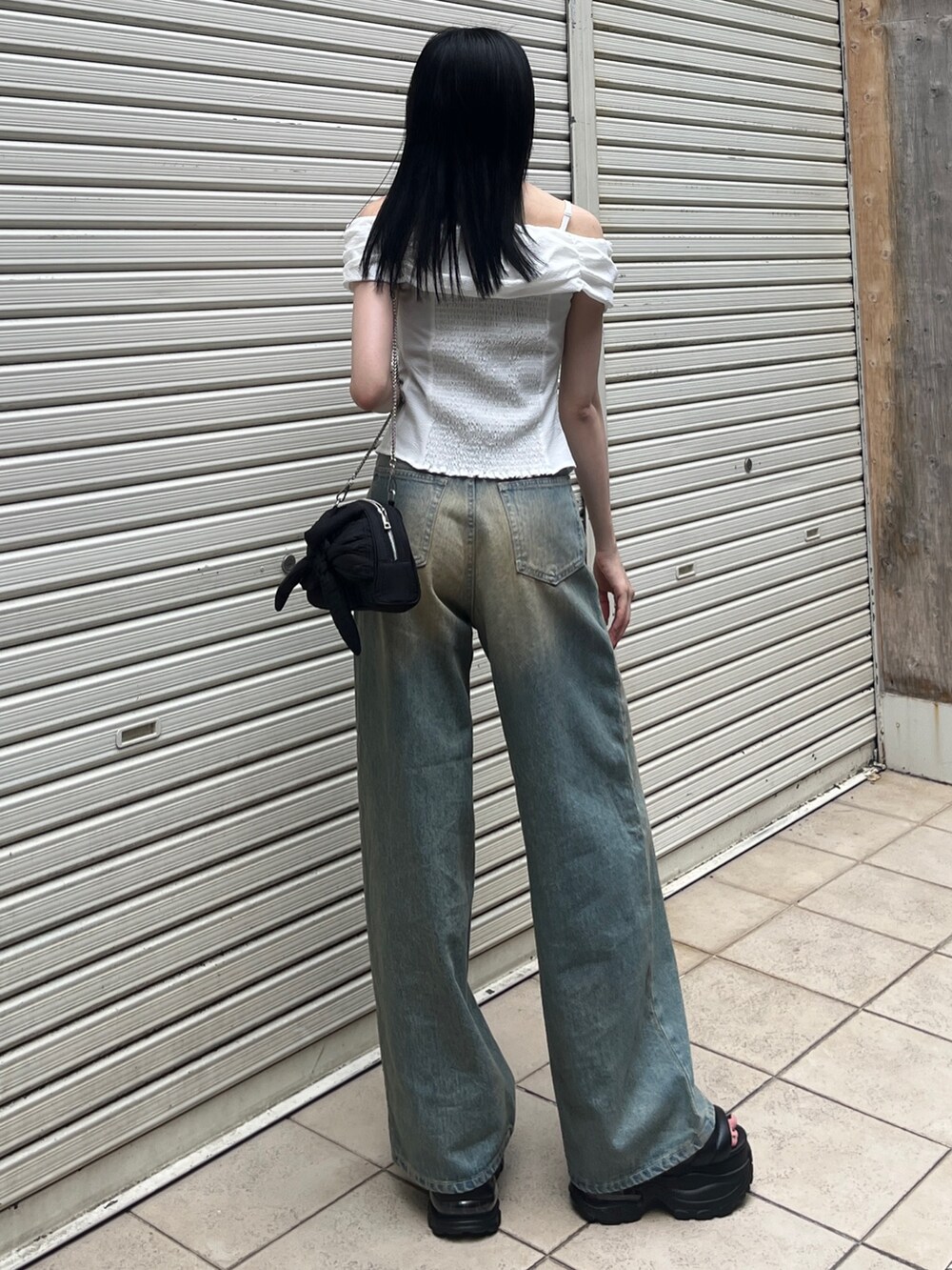 ホワイト系のTシャツ/カットソー、ブルー系のデニムパンツ、ブラック系のハンドバッグを着用したレディースの夏コーディネートの3枚目の写真