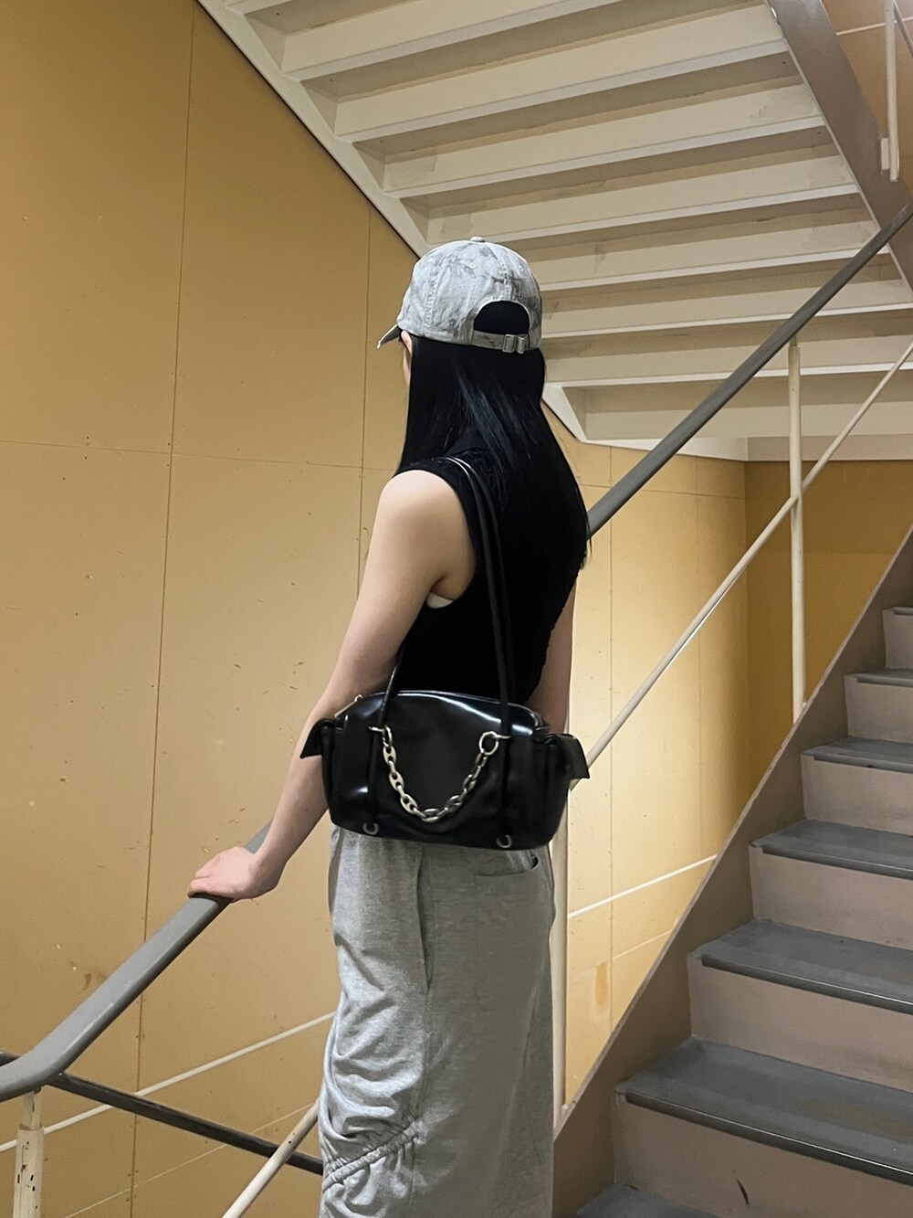 ブラック系のニット/セーター、グレー系のスカート、ブラック系のサンダルを着用したレディースの夏コーディネートの5枚目の写真