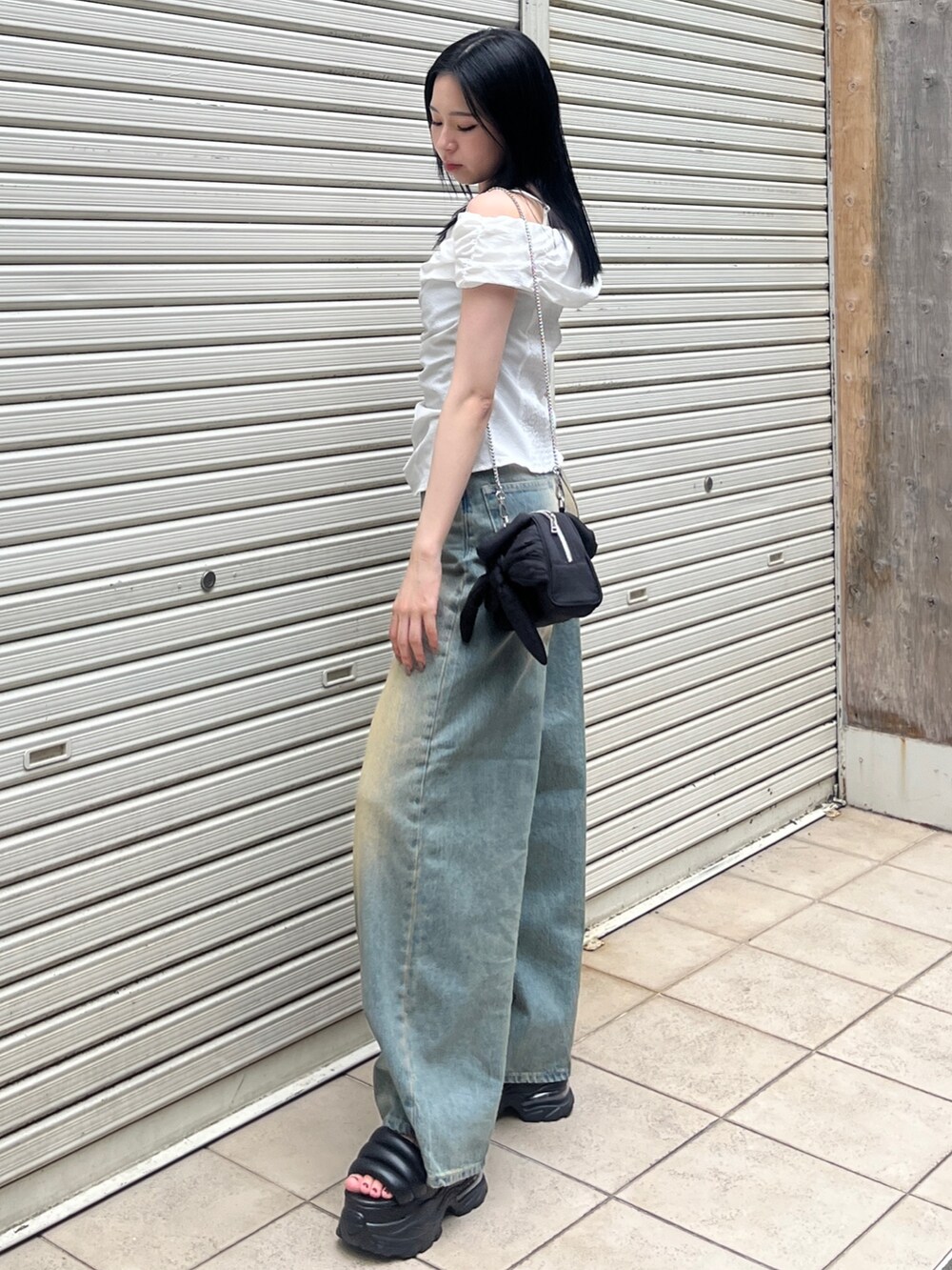 ホワイト系のTシャツ/カットソー、ブルー系のデニムパンツ、ブラック系のハンドバッグを着用したレディースの夏コーディネートの2枚目の写真