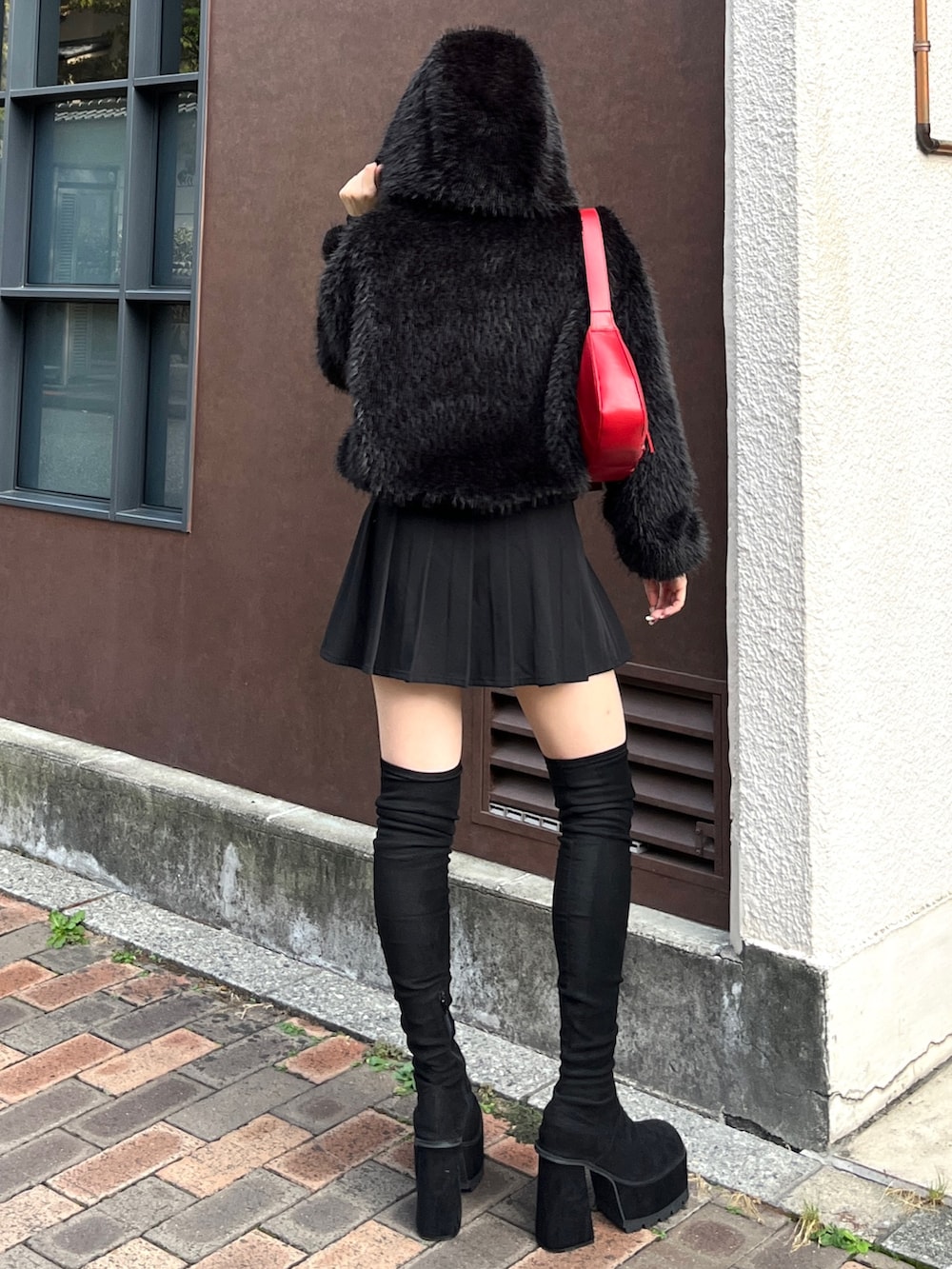 ブラック系のスカート、ブラック系のブルゾン、レッド系のショルダーバッグを着用したレディースの秋コーディネートの3枚目の写真