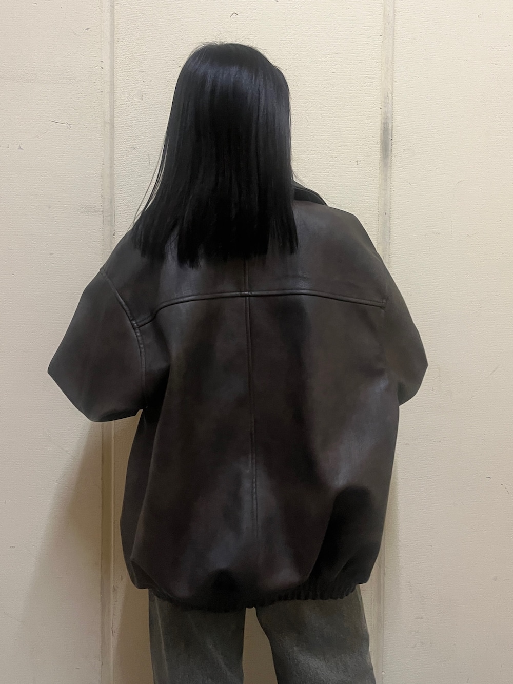 ブラック系のニット/セーター、ブラウン系のブルゾン、ブルー系のデニムパンツを着用したレディースの冬コーディネートの7枚目の写真