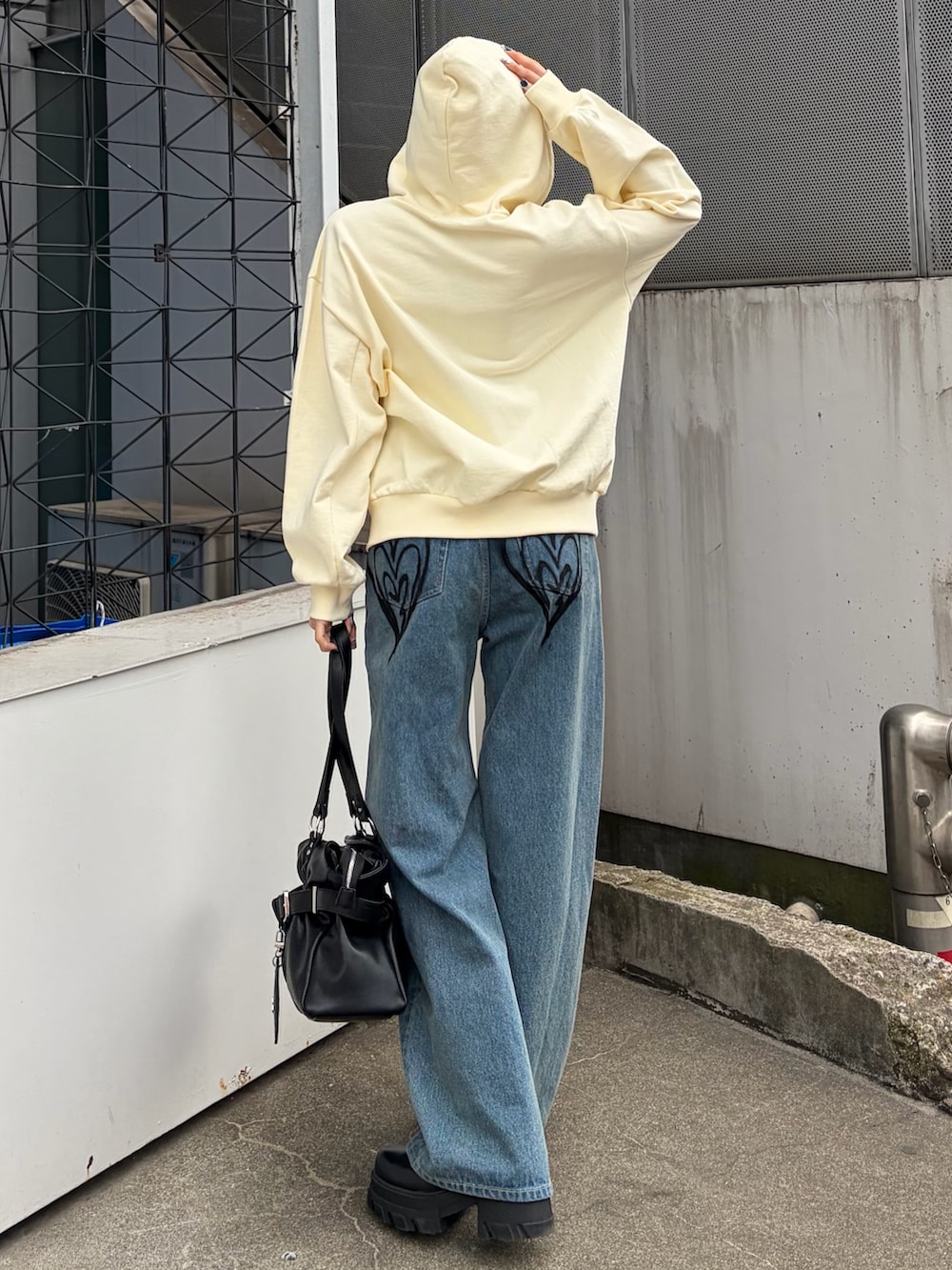 ホワイト系のパーカー、ブルー系のデニムパンツ、ブラック系のトートバッグを着用したレディースの冬コーディネートの2枚目の写真