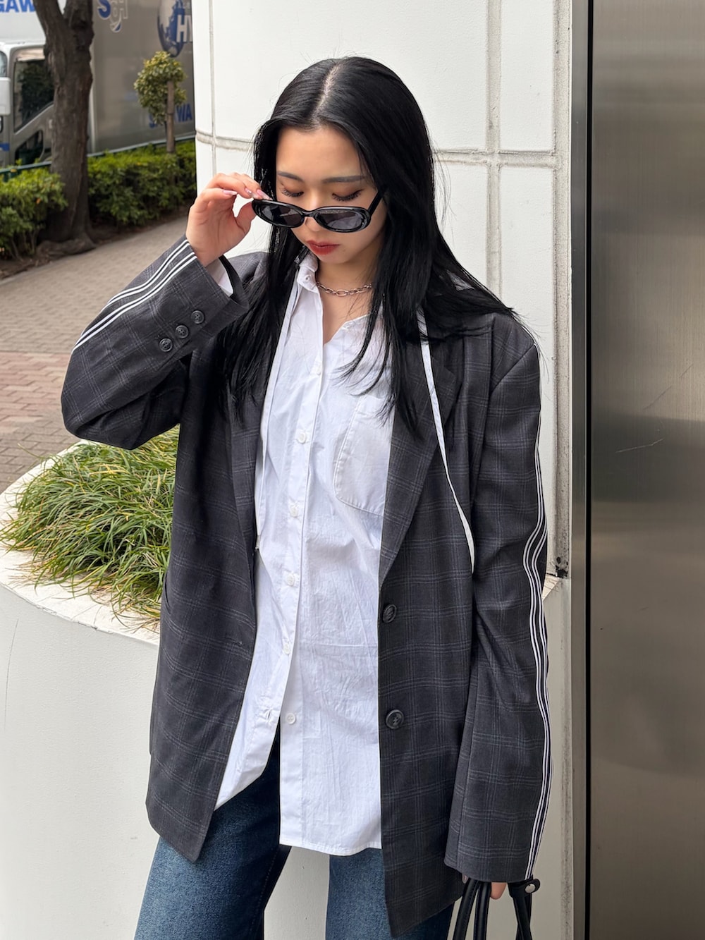 グレー系のテーラードジャケット、ホワイト系のシャツ/ブラウス、ブルー系のデニムパンツを着用したレディースの春コーディネートの6枚目の写真