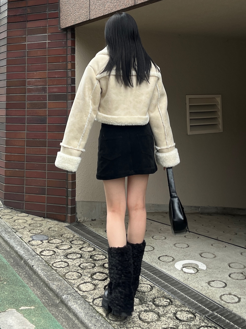 ブラック系のブーツ、ホワイト系のブルゾン、ブラック系のスカートを着用したレディースの冬コーディネートの2枚目の写真