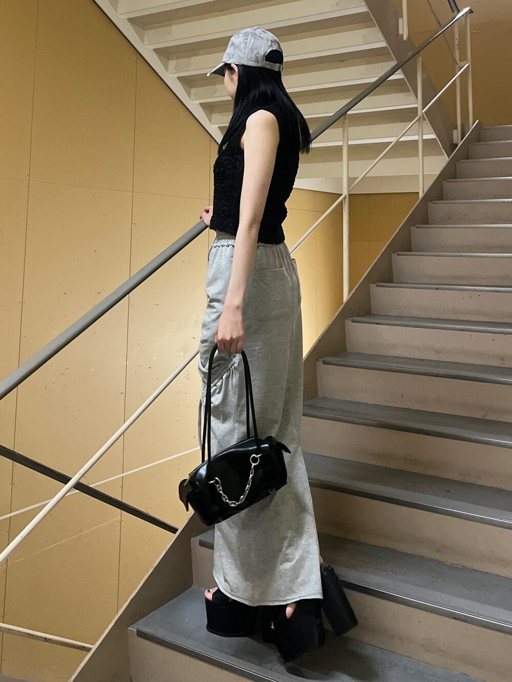 ブラック系のニット/セーター、グレー系のスカート、ブラック系のサンダルを着用したレディースの夏コーディネートの2枚目の写真