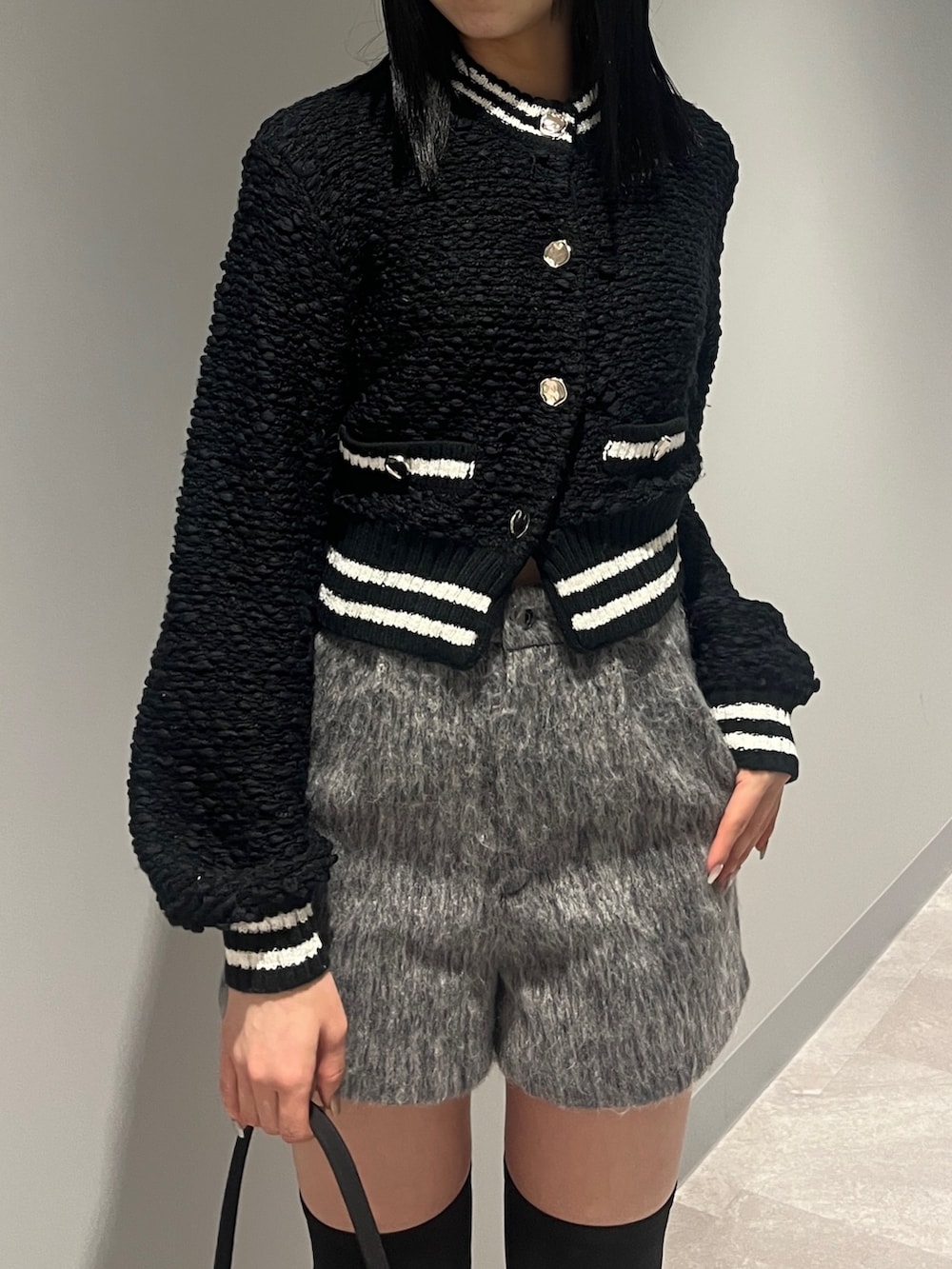 ホワイト系のブルゾン、ブラック系のカーディガン/ボレロ、グレー系のその他パンツを着用したレディースの冬コーディネートの7枚目の写真