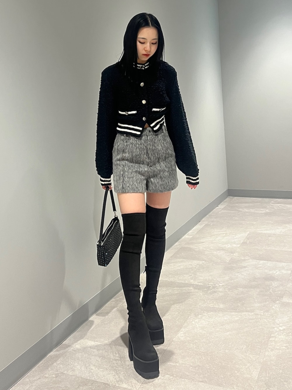 ホワイト系のブルゾン、ブラック系のカーディガン/ボレロ、グレー系のその他パンツを着用したレディースの冬コーディネートの6枚目の写真