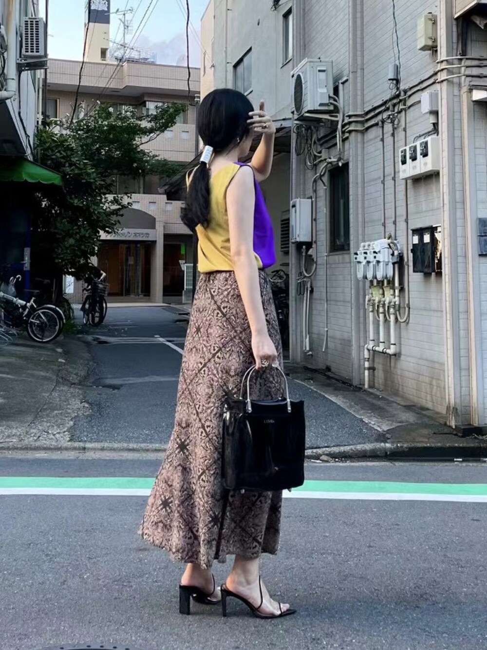 ブラック系のハンドバッグ、パープル系のトップス、ブラック系のその他シューズを着用したレディースの春コーディネートの2枚目の写真