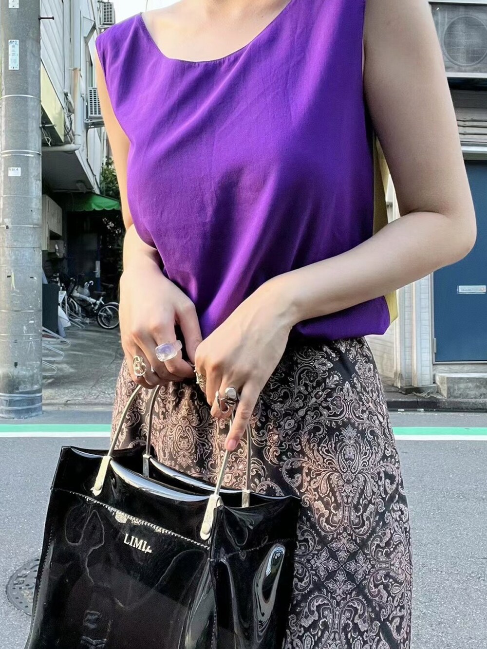 ブラック系のハンドバッグ、パープル系のトップス、ブラック系のその他シューズを着用したレディースの春コーディネートの4枚目の写真