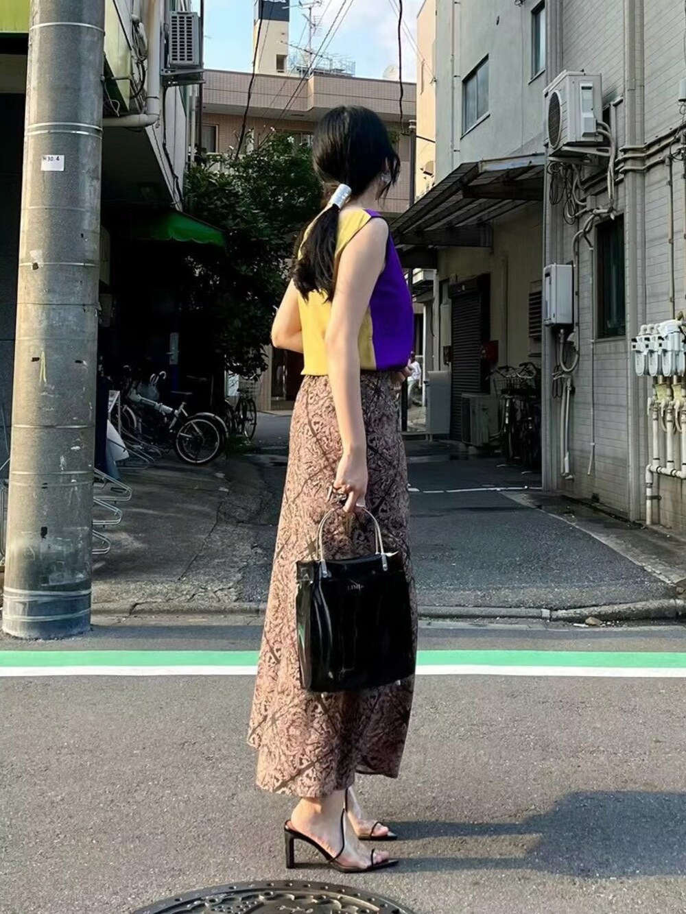 ブラック系のハンドバッグ、パープル系のトップス、ブラック系のその他シューズを着用したレディースの春コーディネートの3枚目の写真