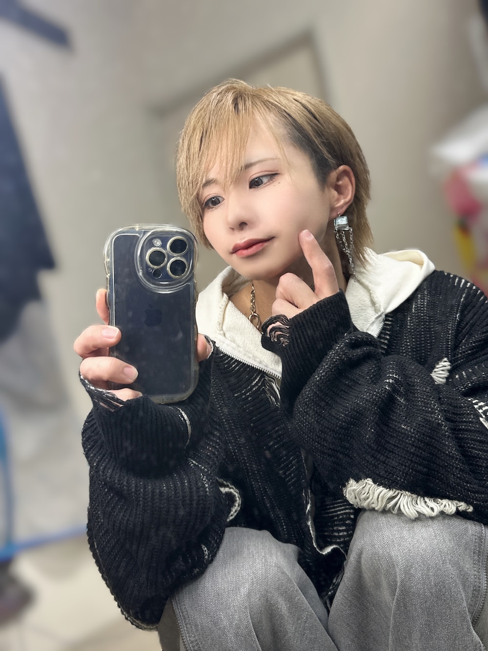 グレー系のデニムパンツ、ホワイト系のスニーカー、ブラック系のカーディガン/ボレロを着用したメンズの冬コーディネートの2枚目の写真