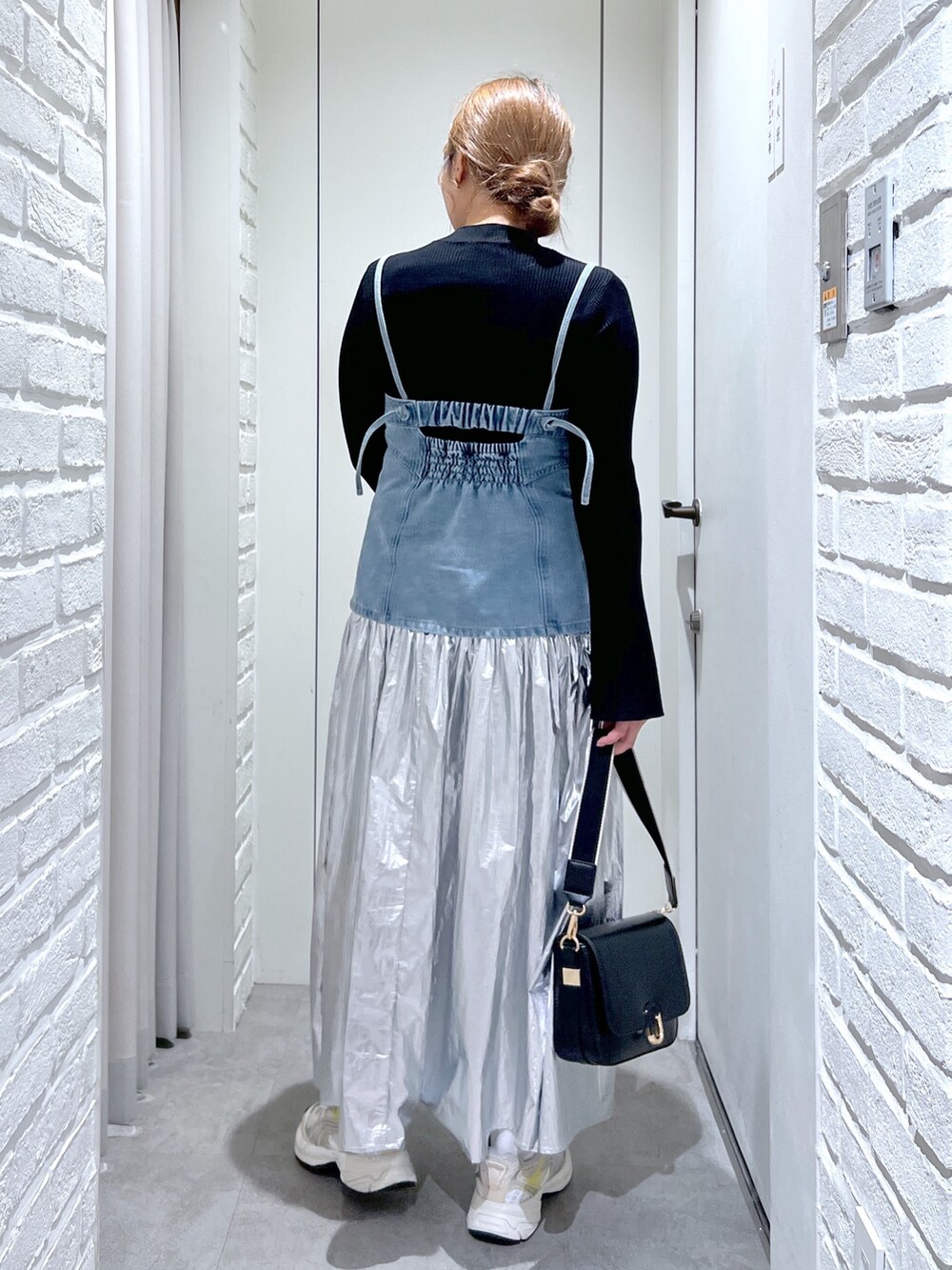 シルバー系のスカート、ブルー系のベスト、ブラック系のニット/セーターを着用したレディースの春コーディネートの4枚目の写真