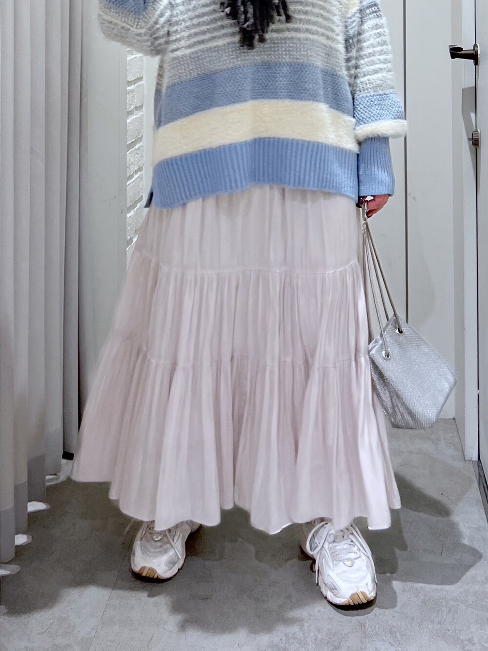 ブルー系のニット/セーター、ホワイト系のスカート、シルバー系のショルダーバッグを着用したレディースの冬コーディネートの6枚目の写真