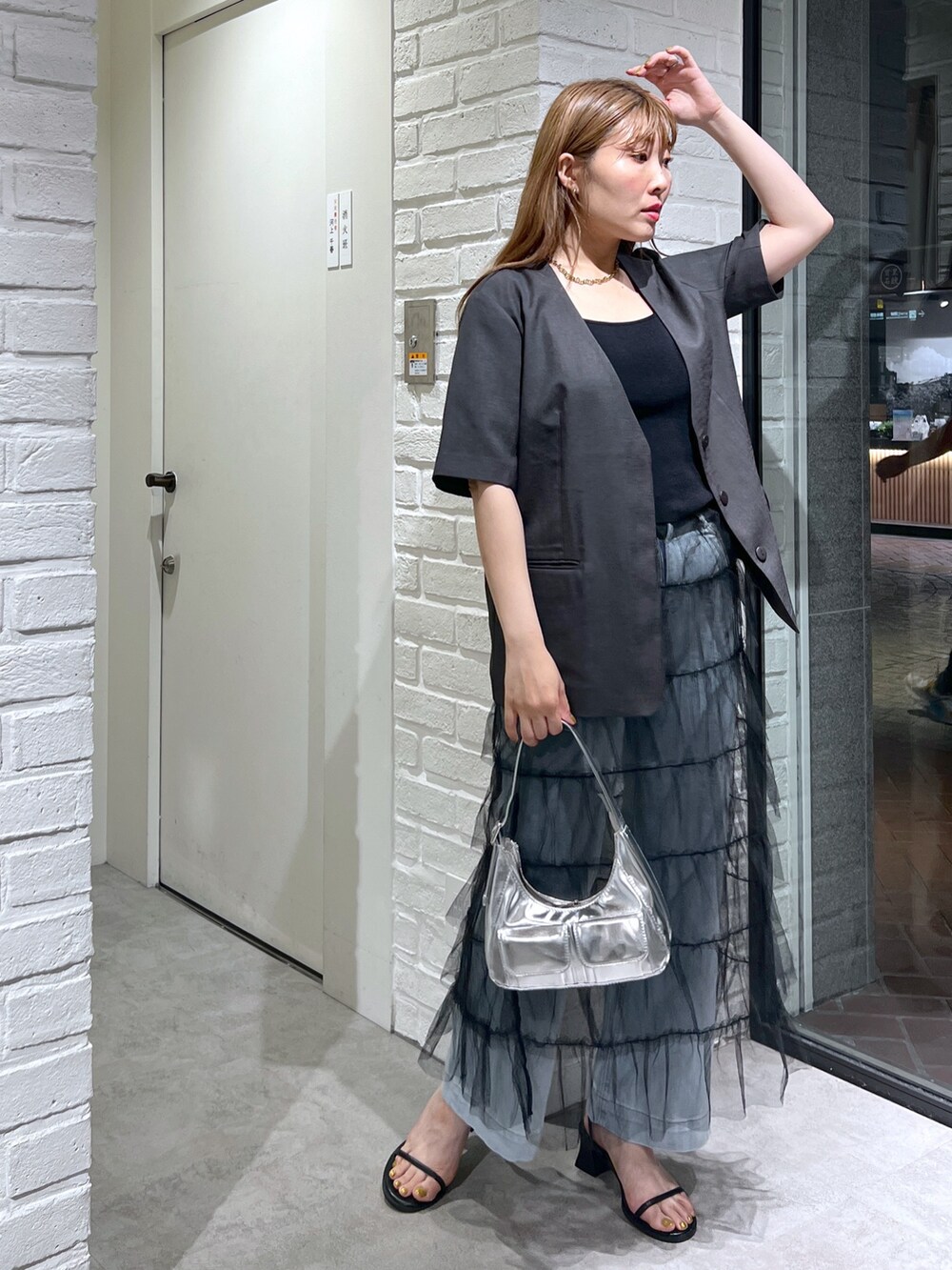 グレー系のノーカラージャケット、ブラック系のスカート、ブルー系のデニムパンツを着用したレディースの夏コーディネートの2枚目の写真