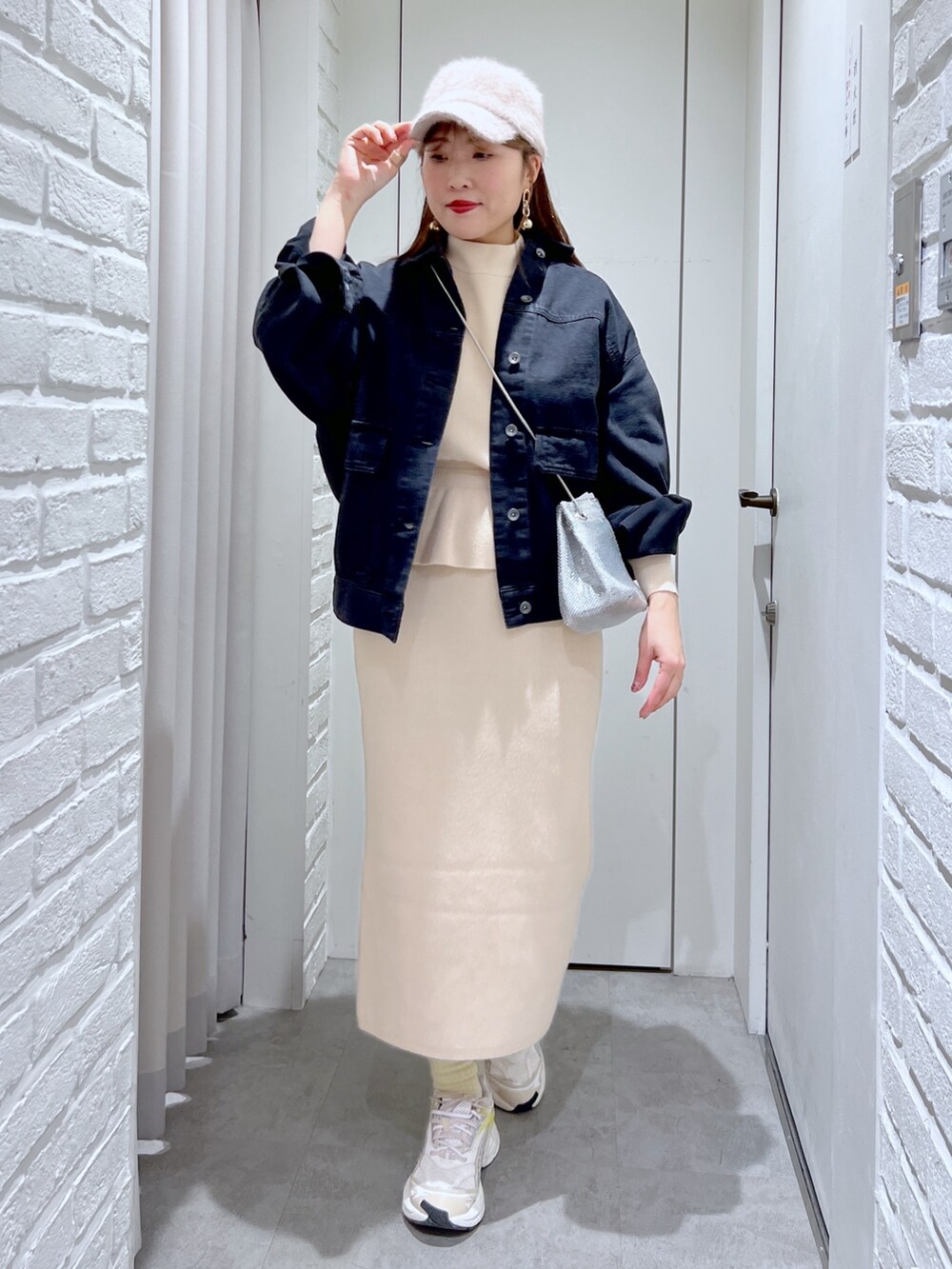 ホワイト系のワンピース、シルバー系のショルダーバッグ、ブラック系のデニムジャケットを着用したレディースの冬コーディネートの2枚目の写真