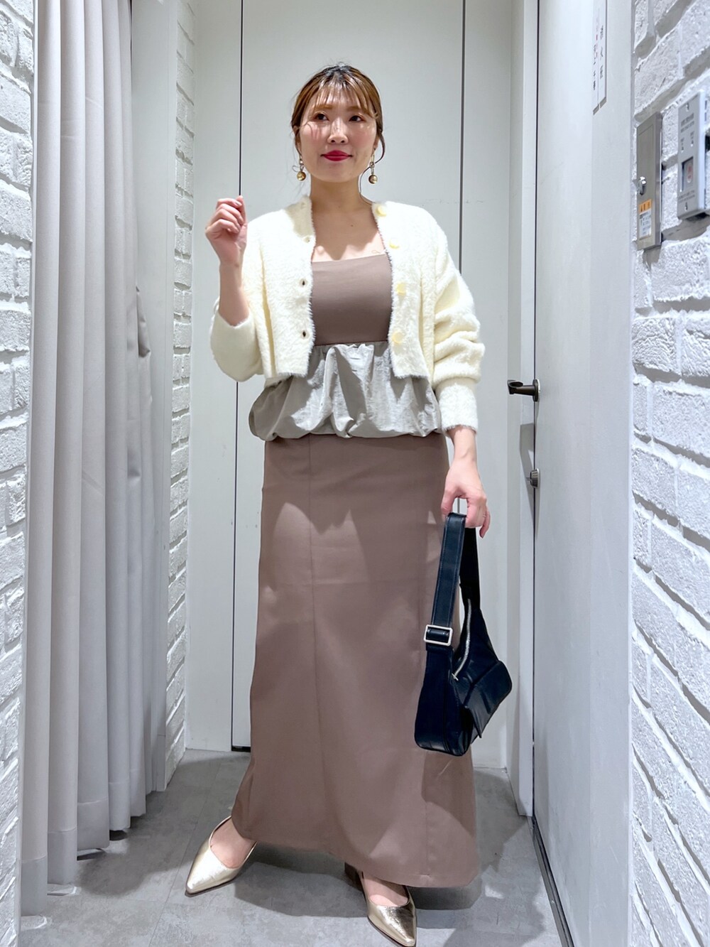 ブラウン系のワンピース、ブラック系のショルダーバッグ、ゴールド系のパンプスを着用したレディースの冬コーディネートの2枚目の写真