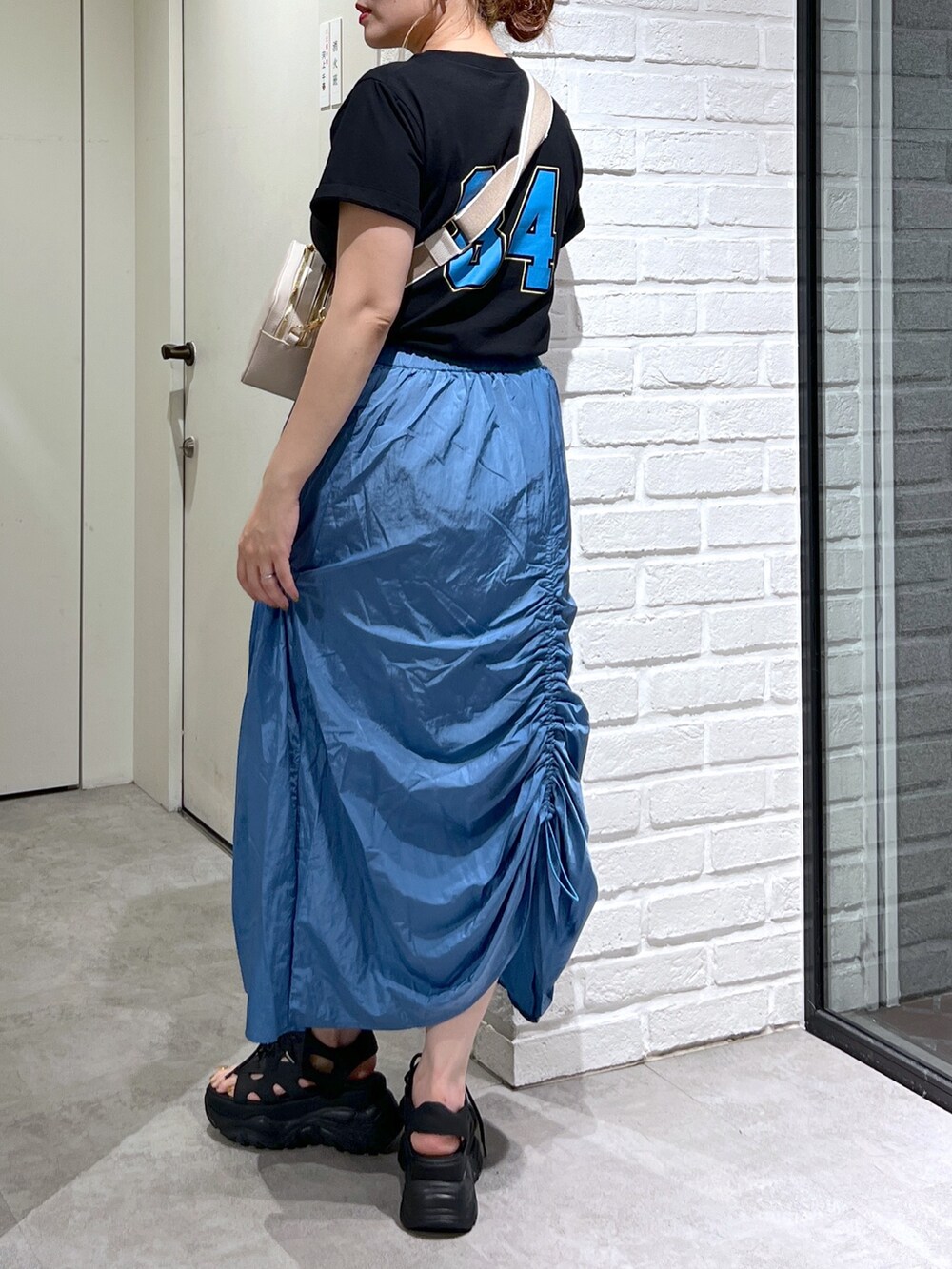 ブルー系のスカート、ブラック系のTシャツ/カットソー、ブラック系のサンダルを着用したレディースの夏コーディネートの5枚目の写真