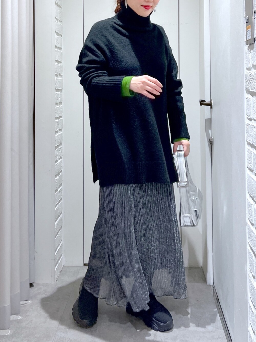 ブラック系のニット/セーター、ブラック系のスカート、ブラック系のブーツを着用したレディースの冬コーディネートの3枚目の写真