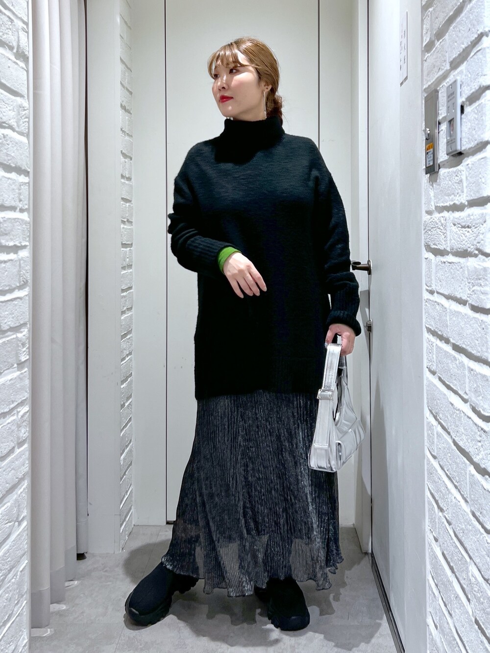 ブラック系のニット/セーター、ブラック系のスカート、ブラック系のブーツを着用したレディースの冬コーディネートの2枚目の写真