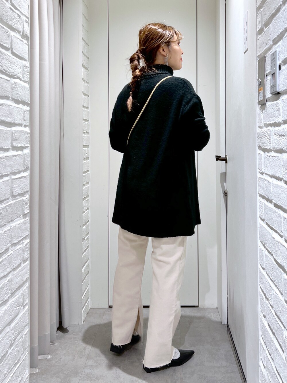 ブラック系のニット/セーター、ホワイト系のデニムパンツ、ブラック系のバレエシューズを着用したレディースの冬コーディネートの2枚目の写真