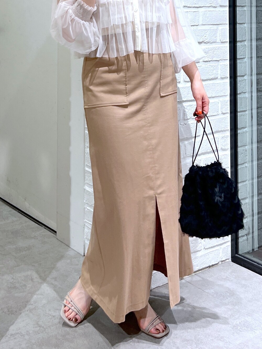 ブラウン系のスカート、ブラック系のハンドバッグ、グレー系のサンダルを着用したレディースの夏コーディネートの7枚目の写真