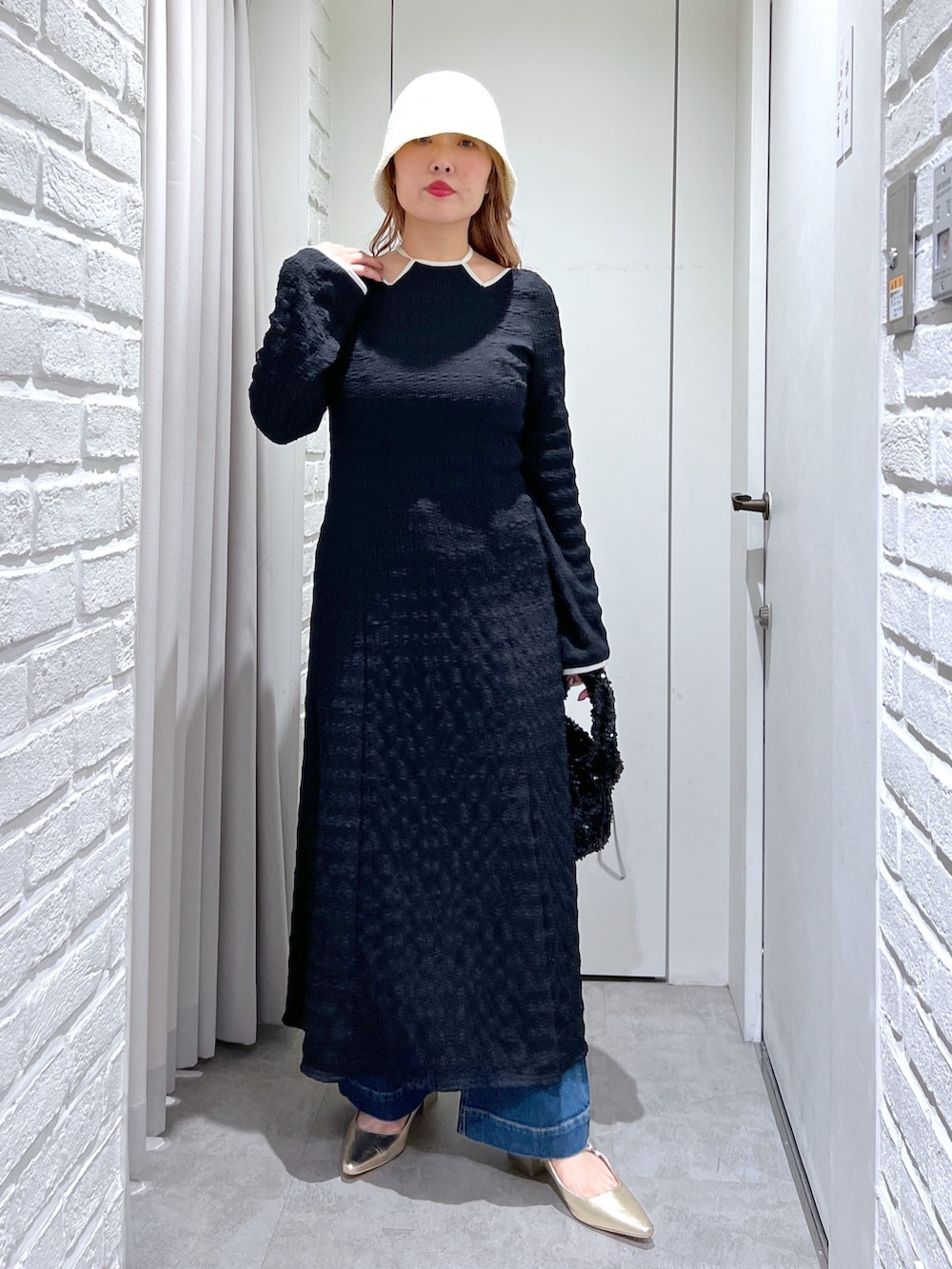 ブラック系のワンピース、ブルー系のデニムパンツ、ブラック系のハンドバッグを着用したレディースの春コーディネートの2枚目の写真