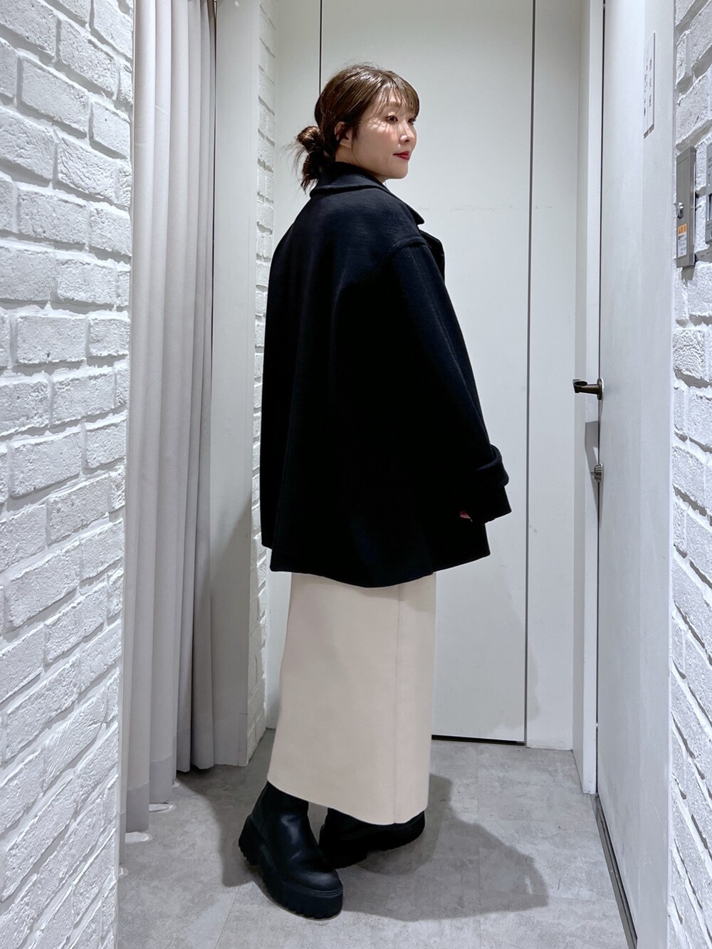 ブラック系のピーコート、ホワイト系のワンピース、ブラック系のTシャツ/カットソーを着用したレディースの冬コーディネートの3枚目の写真