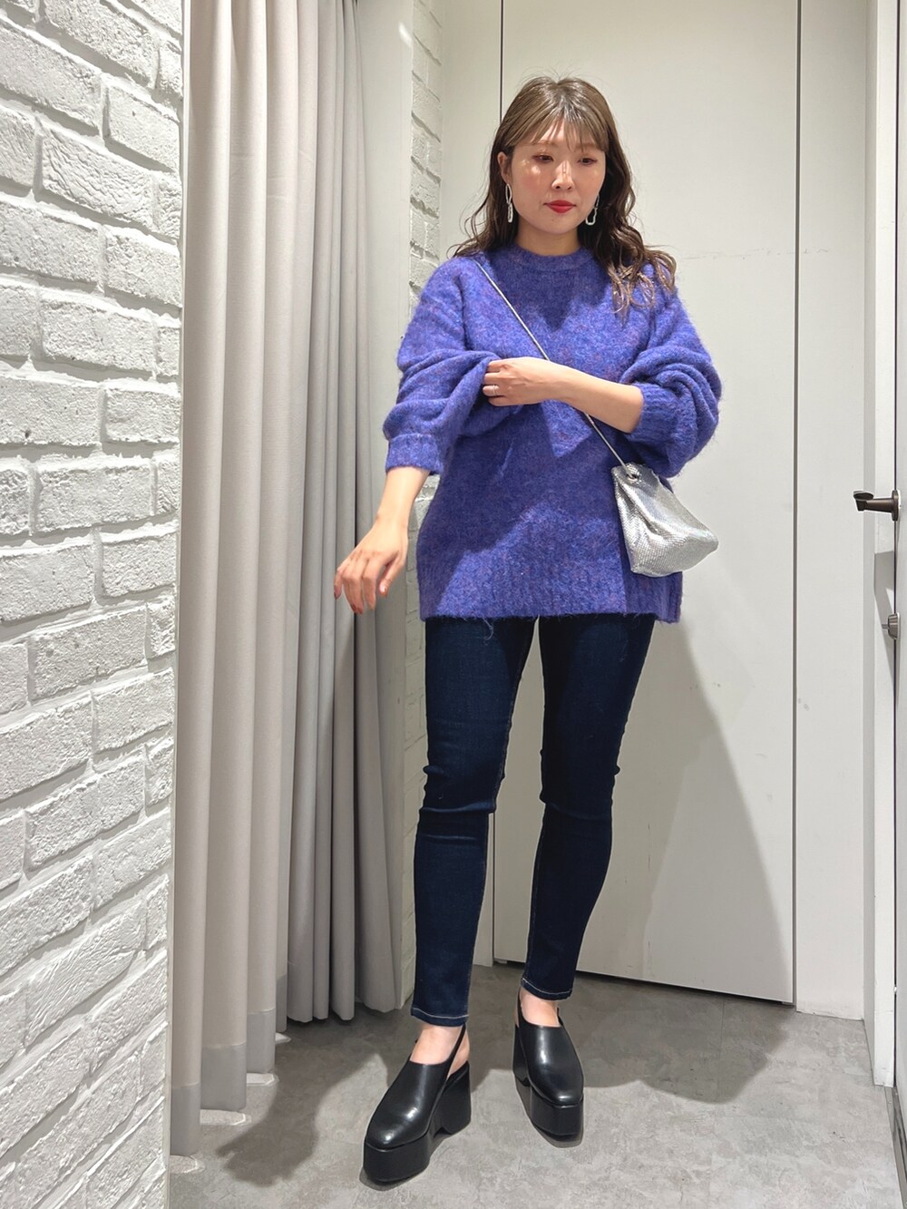 ブルー系のニット/セーター、ブルー系のデニムパンツ、ブラック系のサンダルを着用したレディースの秋コーディネートの2枚目の写真