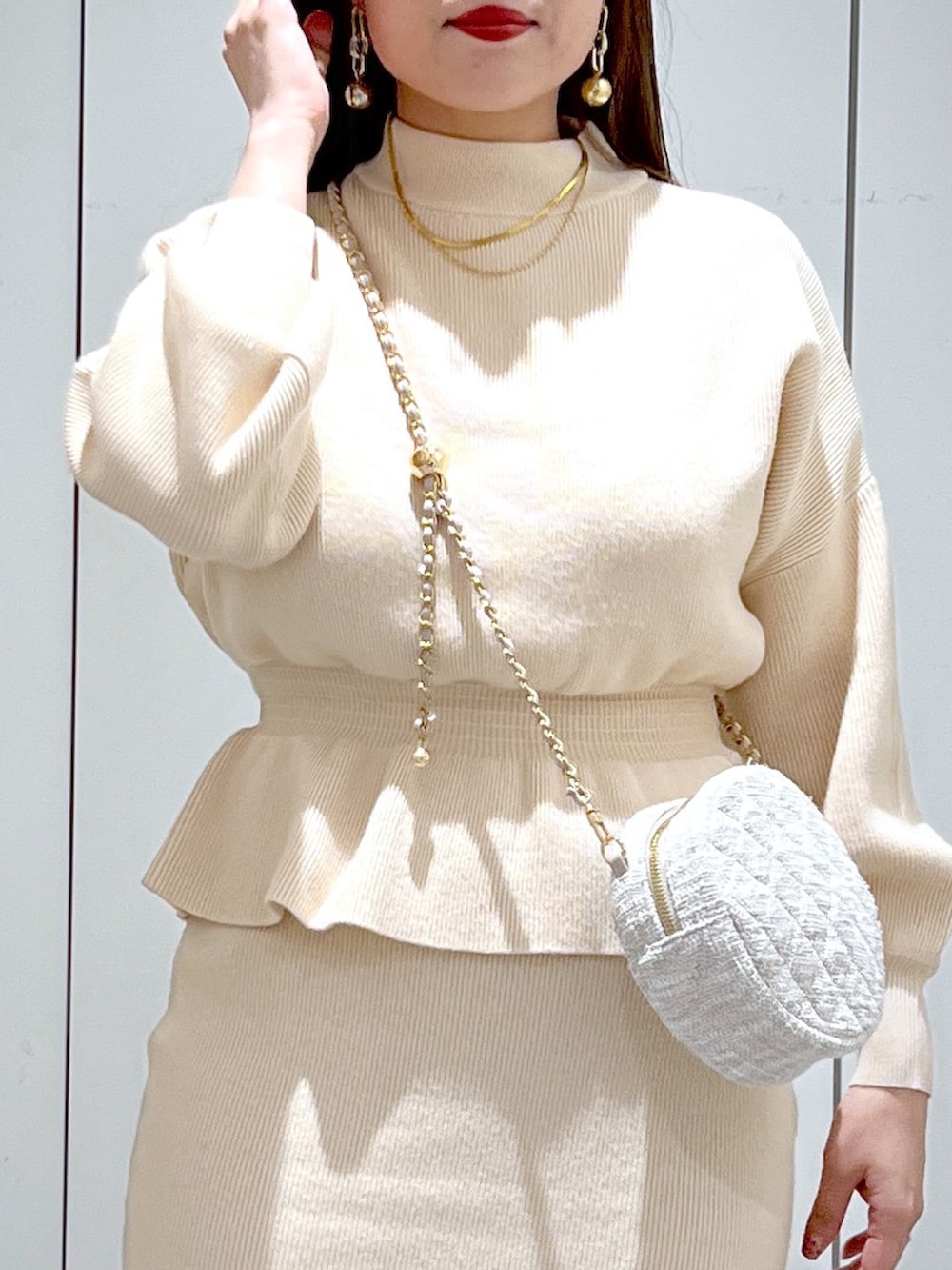 ホワイト系のワンピース、ブラック系のブーツ、ベージュ系のショルダーバッグを着用したレディースの冬コーディネートの6枚目の写真