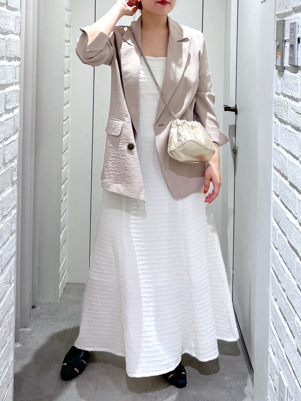 ホワイト系のワンピース、ゴールド系のショルダーバッグ、ブラック系のスリッポンを着用したレディースの春コーディネートの6枚目の写真