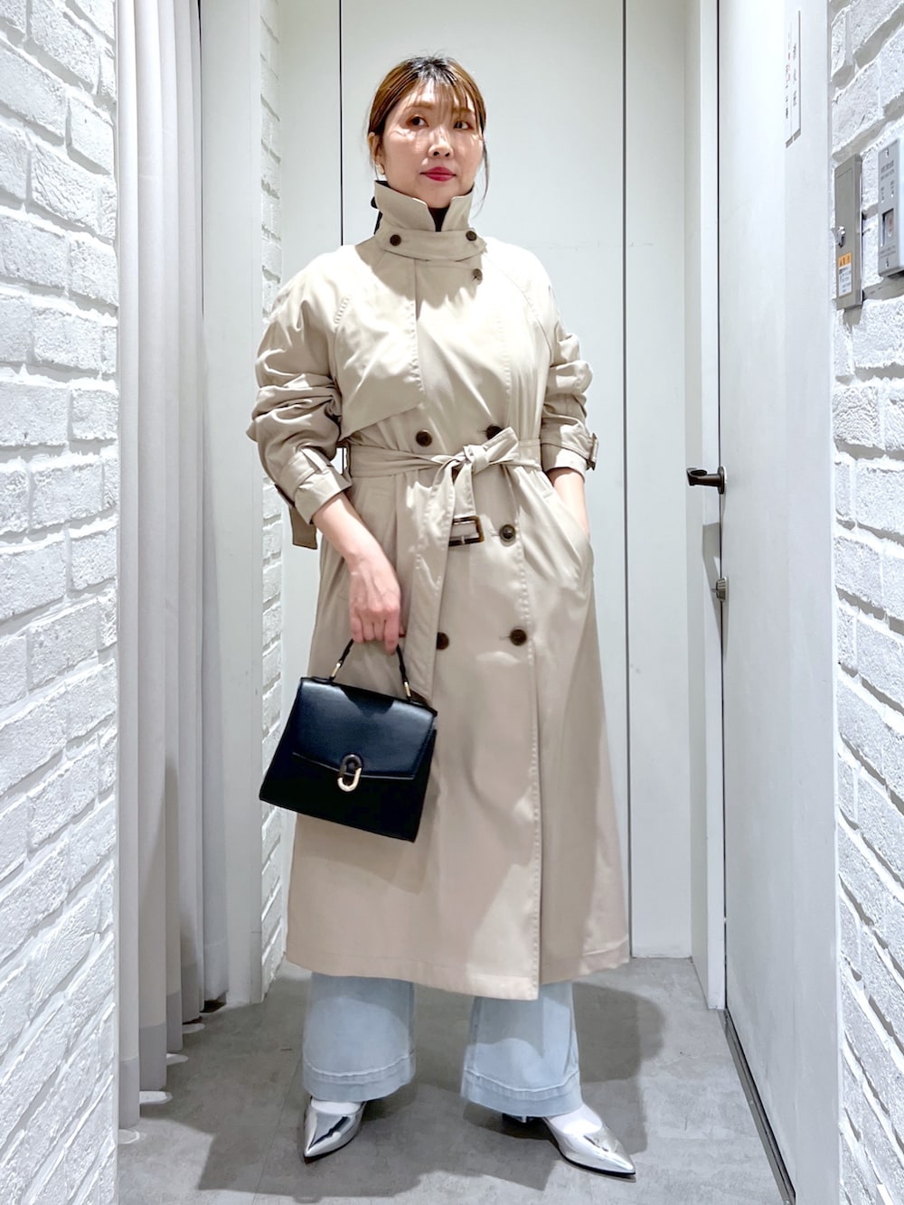 ベージュ系のトレンチコート、ブラック系のショルダーバッグ、ブルー系のデニムパンツを着用したレディースの春コーディネートの3枚目の写真